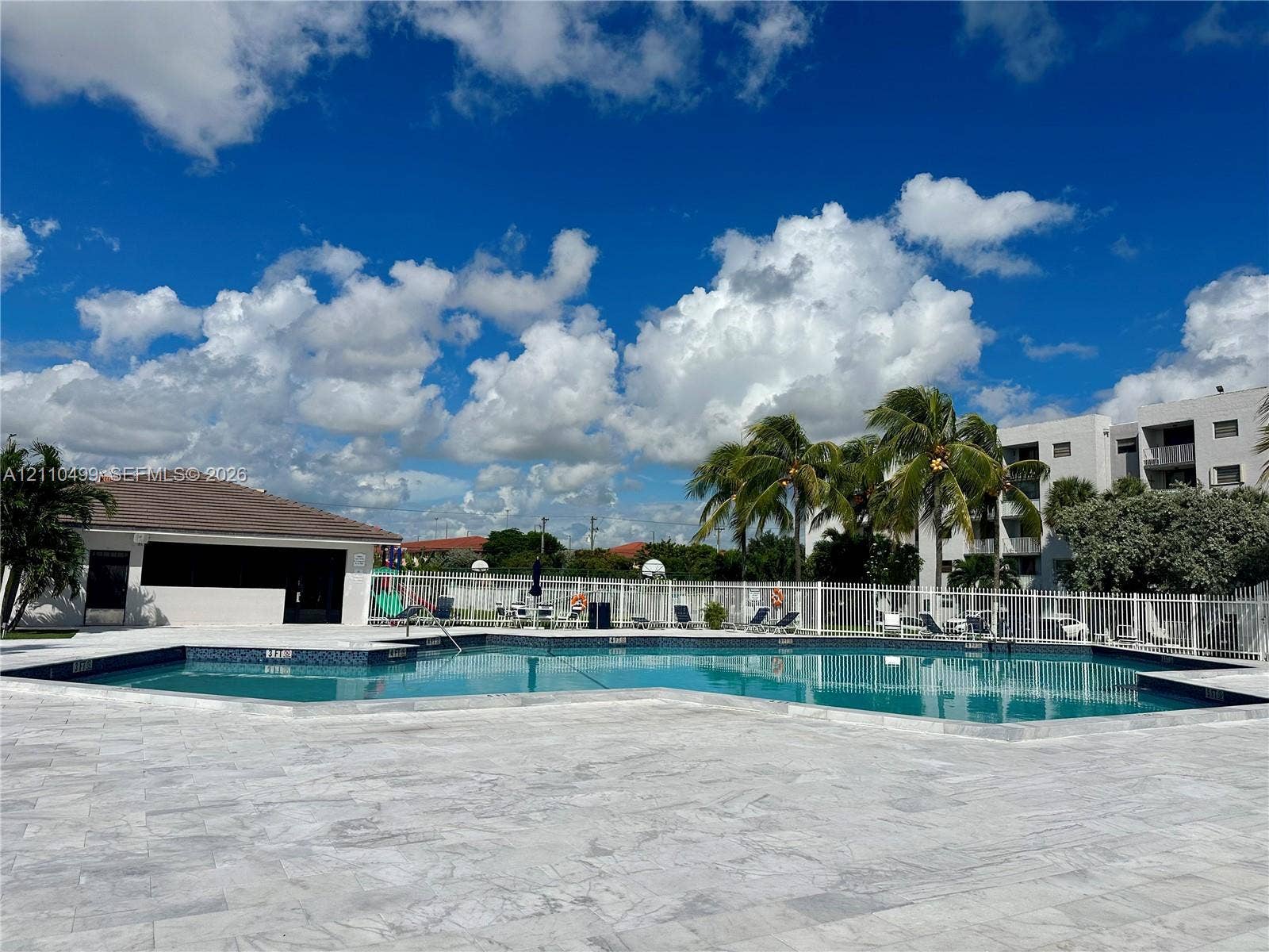8145 NW 7th Street, #308, Miami, Miami, FL 33126 In-ground swimming pool with a tiled waterline and expansive stone paver deck, enclosed by perimeter fencing