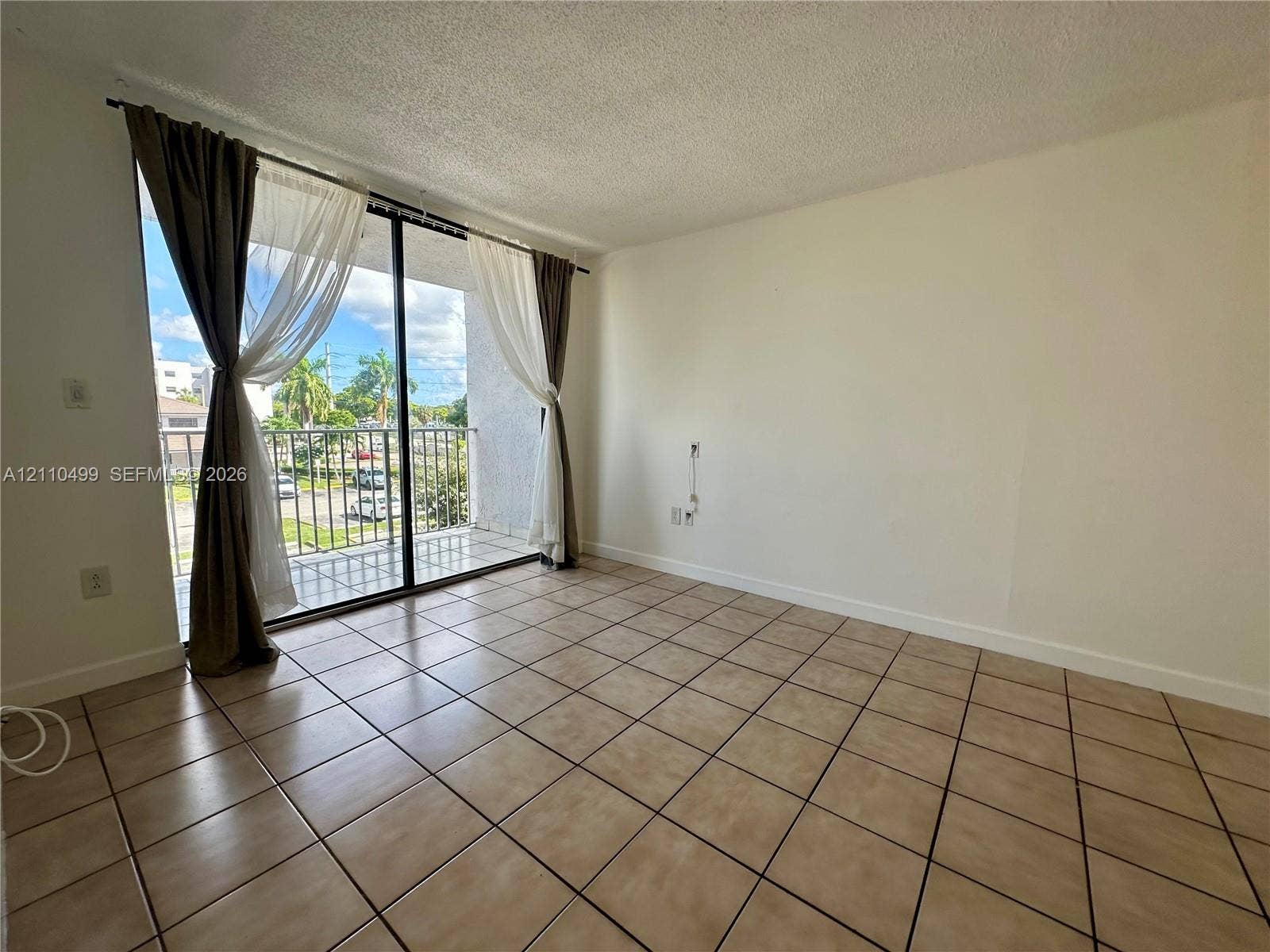 8145 NW 7th Street, #308, Miami, Miami, FL 33126 Living area featuring ceramic tile flooring, sliding glass doors, and a private balcony with metal railing