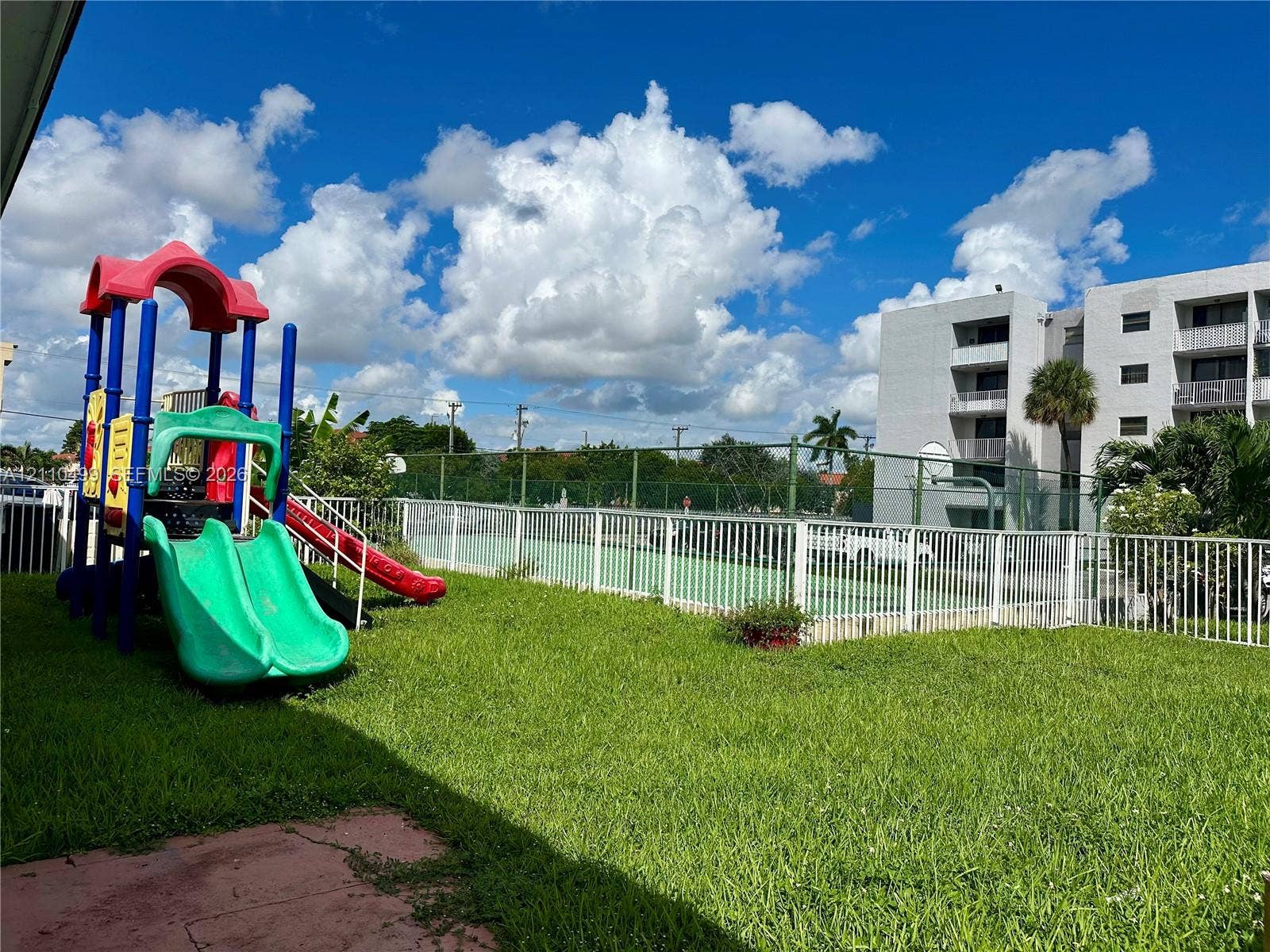 8145 NW 7th Street, #308, Miami, Miami, FL 33126 Common area featuring a grass lawn, fenced-in tennis court, and play equipment