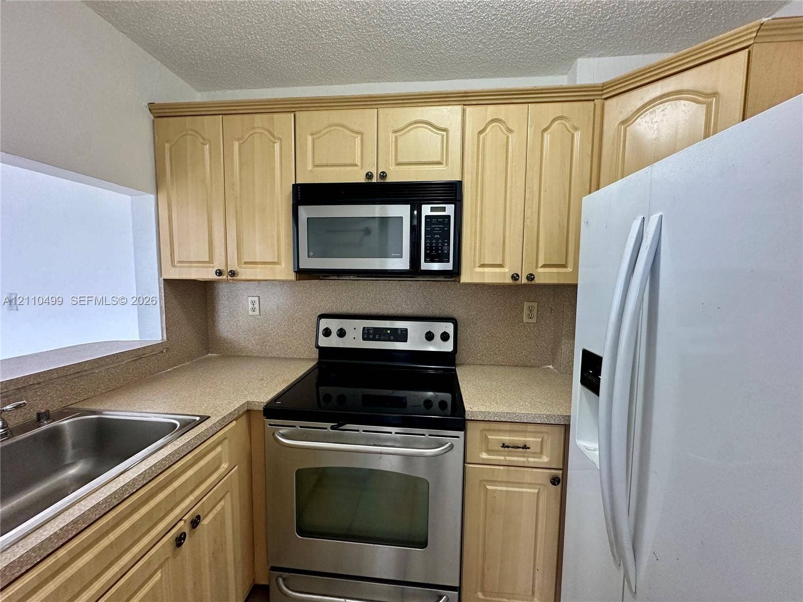 8145 NW 7th Street, #308, Miami, Miami, FL 33126 Kitchen featuring light-finish cabinetry, solid-surface countertops, stainless steel electric range, over-the-range microwave, and stainless steel sink