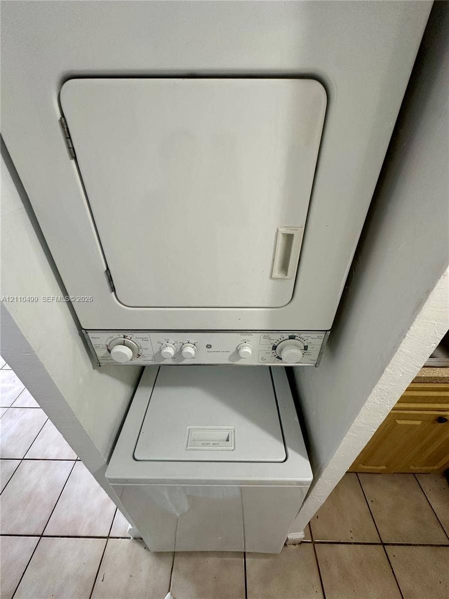 8145 NW 7th Street, #308, Miami, Miami, FL 33126 Stacked laundry unit with top-loading washer and front-loading dryer, set within an alcove featuring ceramic tile flooring