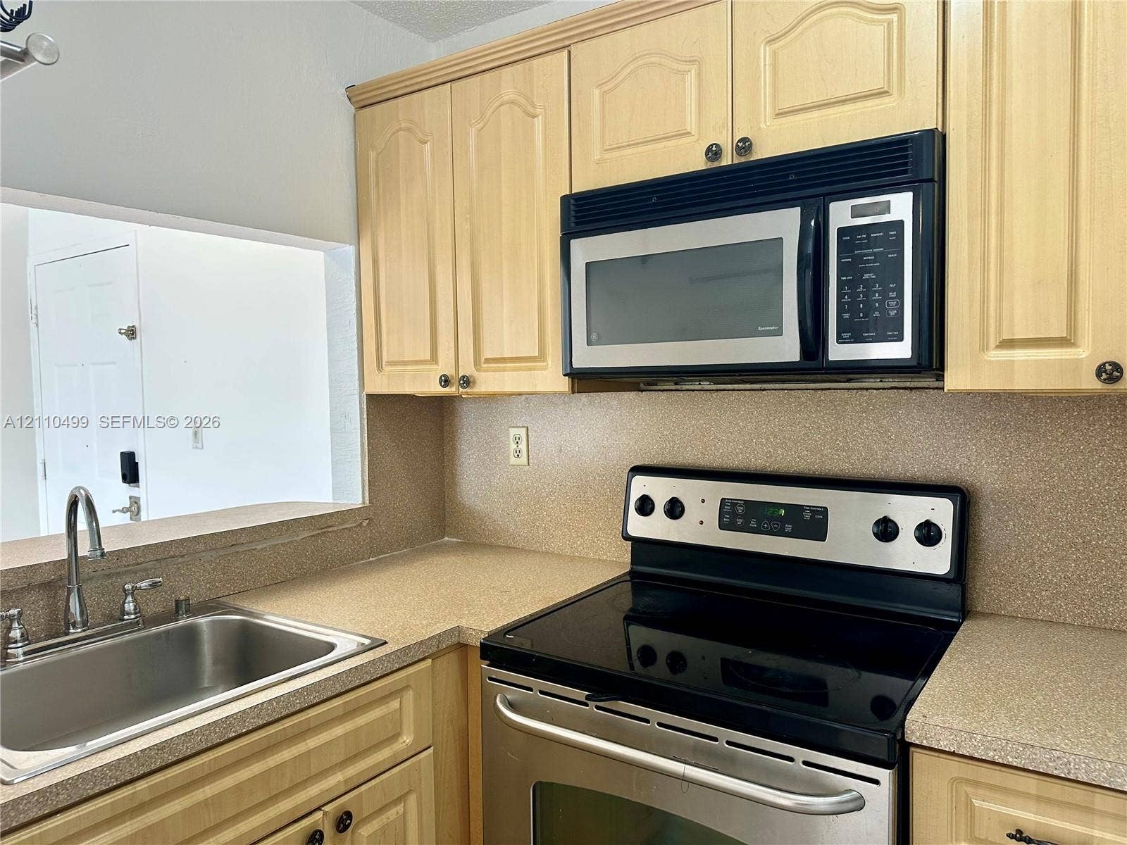 8145 NW 7th Street, #308, Miami, Miami, FL 33126 Kitchen featuring light-finish cabinetry, stainless steel microwave, stainless steel range with electric glass cooktop, solid-surface countertops, and a stainless steel sink with a high-arch faucet