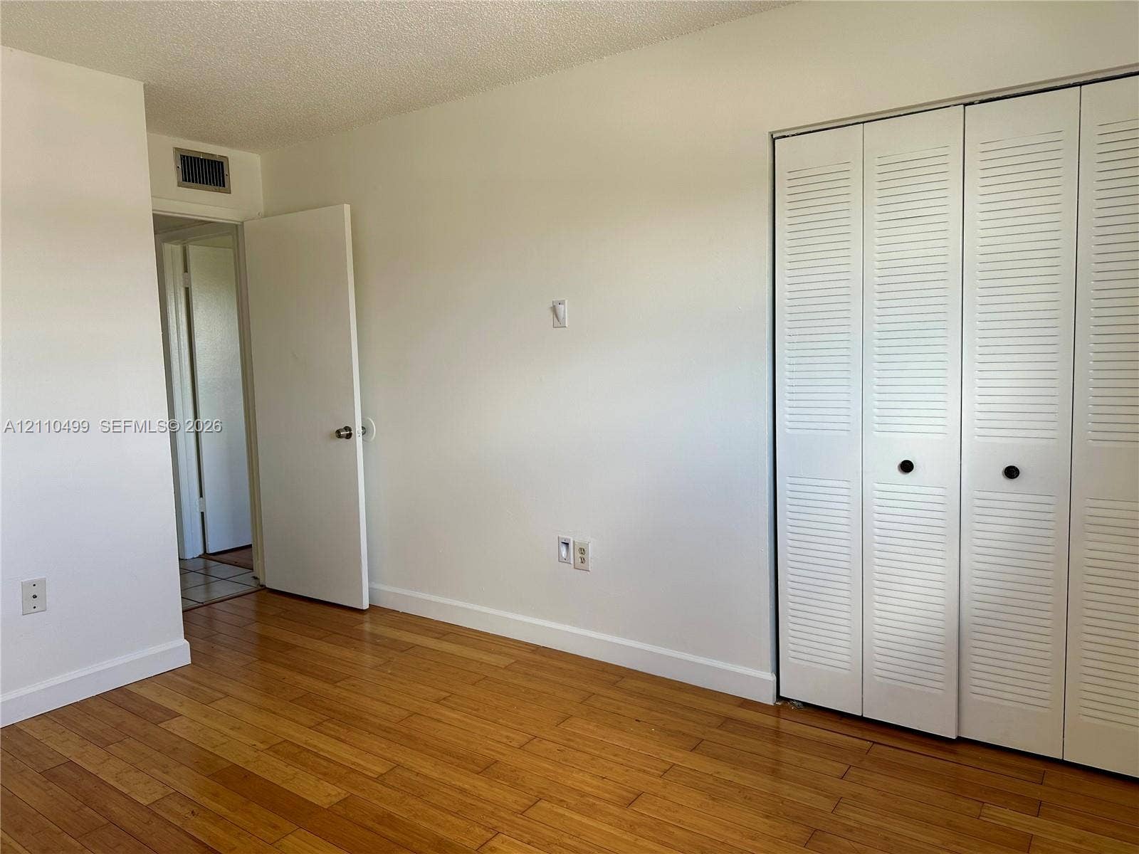 8145 NW 7th Street, #308, Miami, Miami, FL 33126 Wood-finish flooring and white louvered bifold closet doors
