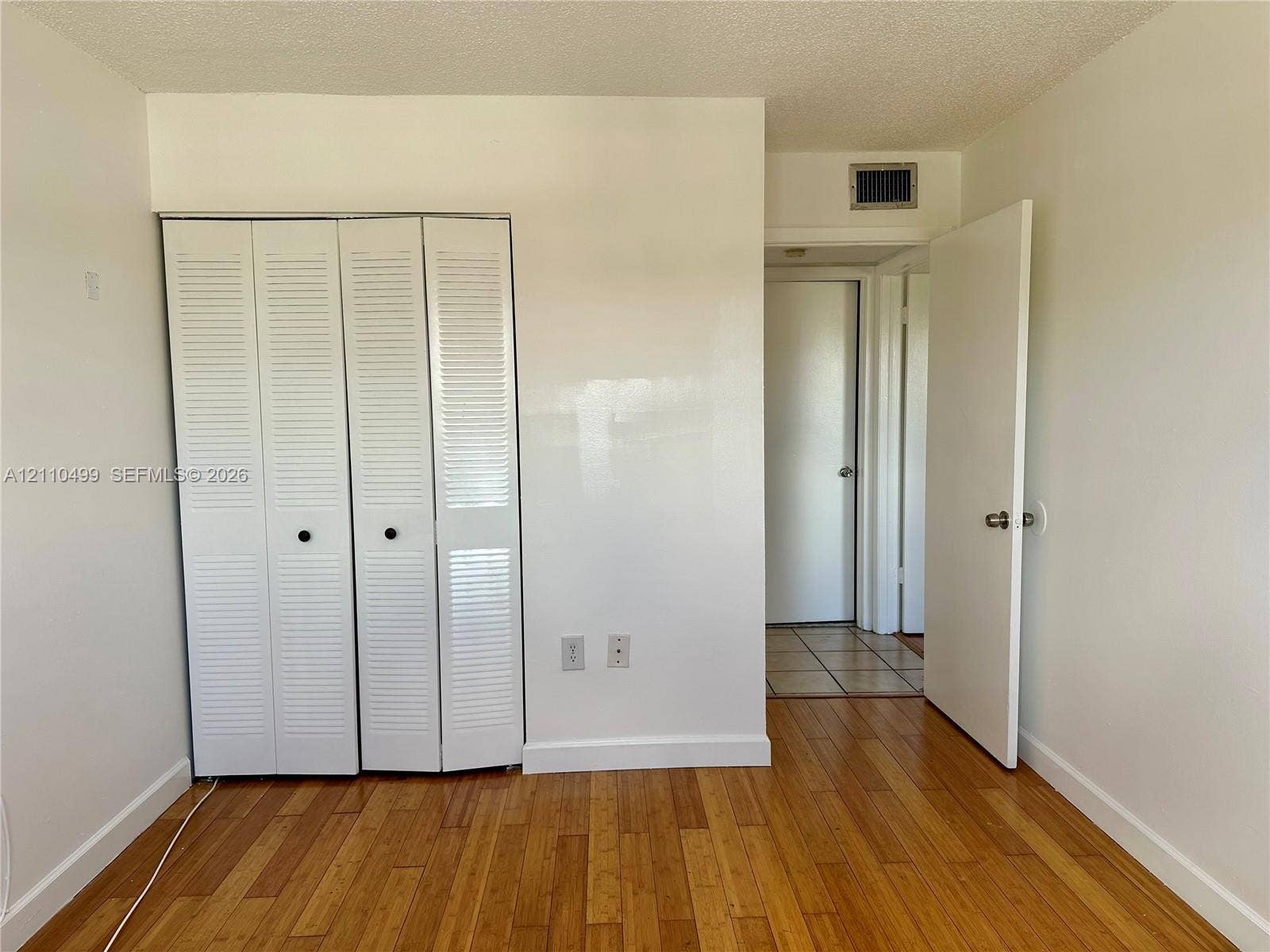8145 NW 7th Street, #308, Miami, Miami, FL 33126 Interior space featuring wood-finish flooring and white louvered bifold closet doors
