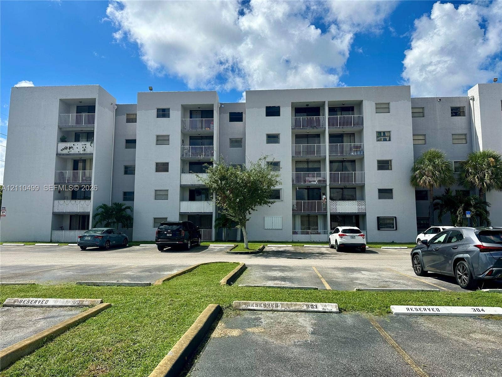 8145 NW 7th Street, #308, Miami, Miami, FL 33126 Multi-story concrete residential building featuring private balconies, designated parking spaces, and established palms
