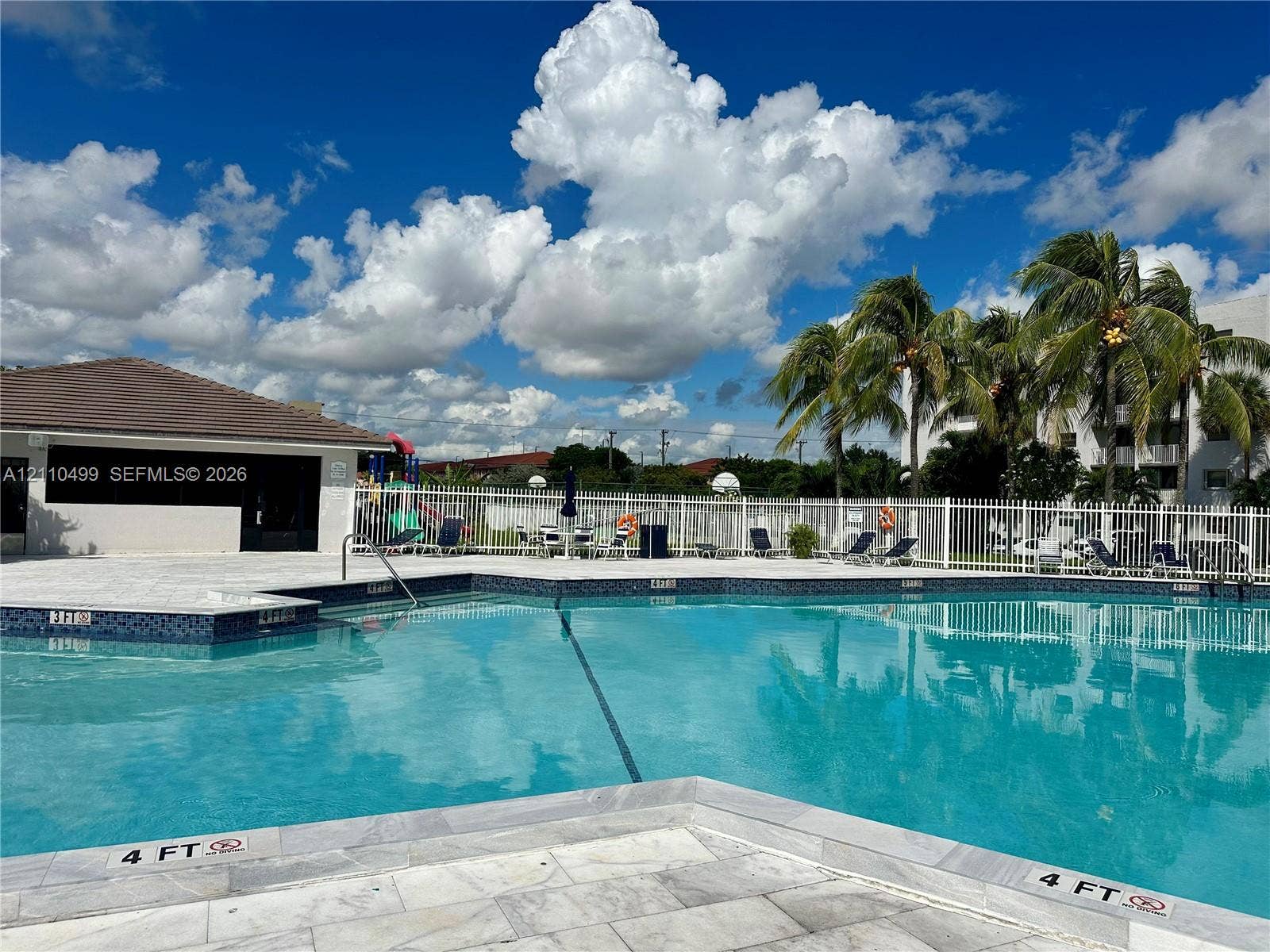 8145 NW 7th Street, #308, Miami, Miami, FL 33126 Swimming pool with stone-finish decking, tiled waterline, and white metal perimeter fencing