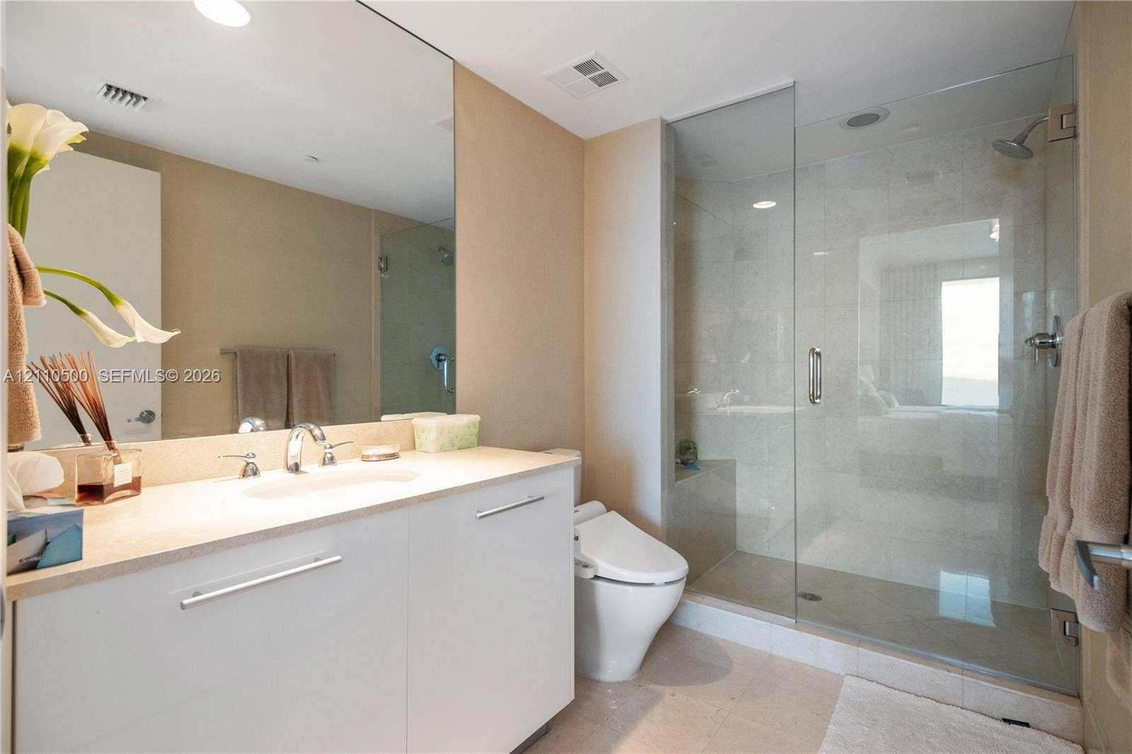 2711 S Ocean Drive, #2205, Hollywood, Hollywood, FL 33019 White cabinetry vanity with a solid surface countertop, an expansive wall-mounted mirror, and a glass-enclosed walk-in shower with tile surround