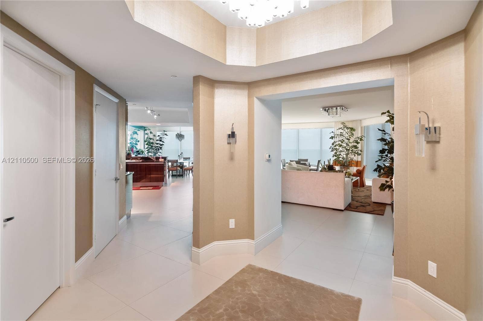 2711 S Ocean Drive, #2205, Hollywood, Hollywood, FL 33019 Foyer featuring a recessed tray ceiling, large-format tile flooring, textured wall finishes, and wall-mounted metal sconces