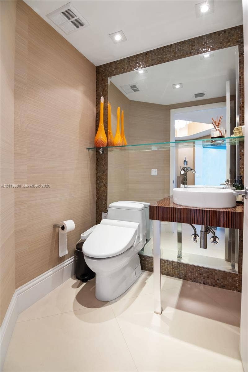 2711 S Ocean Drive, #2205, Hollywood, Hollywood, FL 33019 Floating vanity with a circular vessel sink, wall-mounted faucet, textured wallpaper, mosaic tile backsplash, and large-format floor tile