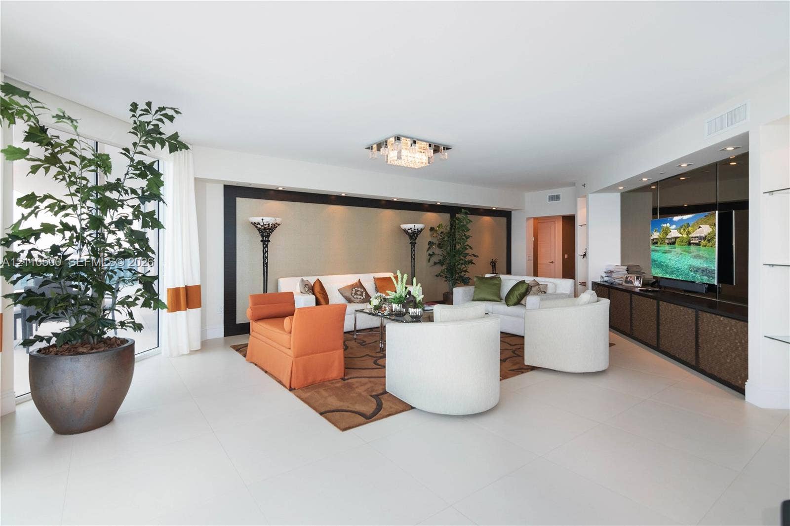 2711 S Ocean Drive, #2205, Hollywood, Hollywood, FL 33019 Living area featuring oversized floor-to-ceiling windows, large-format tile flooring, built-in entertainment cabinetry with integrated recessed lighting, and a tiered crystalline flush-mount ceiling fixture
