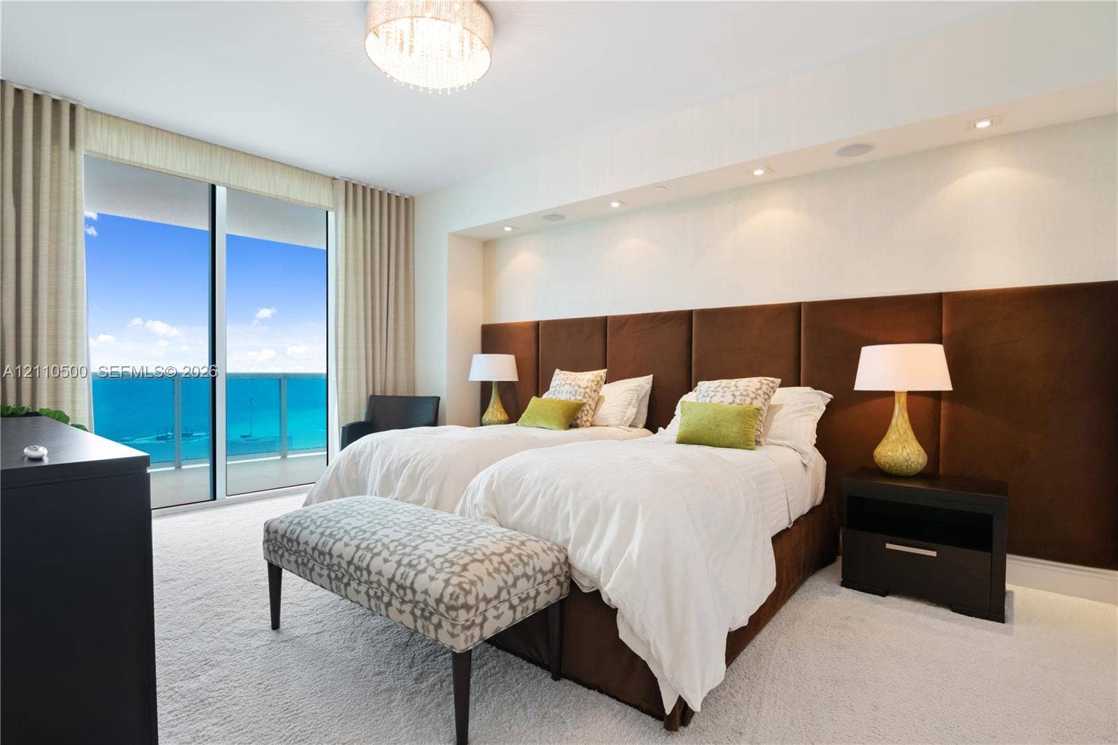 2711 S Ocean Drive, #2205, Hollywood, Hollywood, FL 33019 Floor-to-ceiling glass sliding doors opening to a balcony, custom brown upholstered headboard wall, recessed ceiling lighting, and a drum-style chandelier