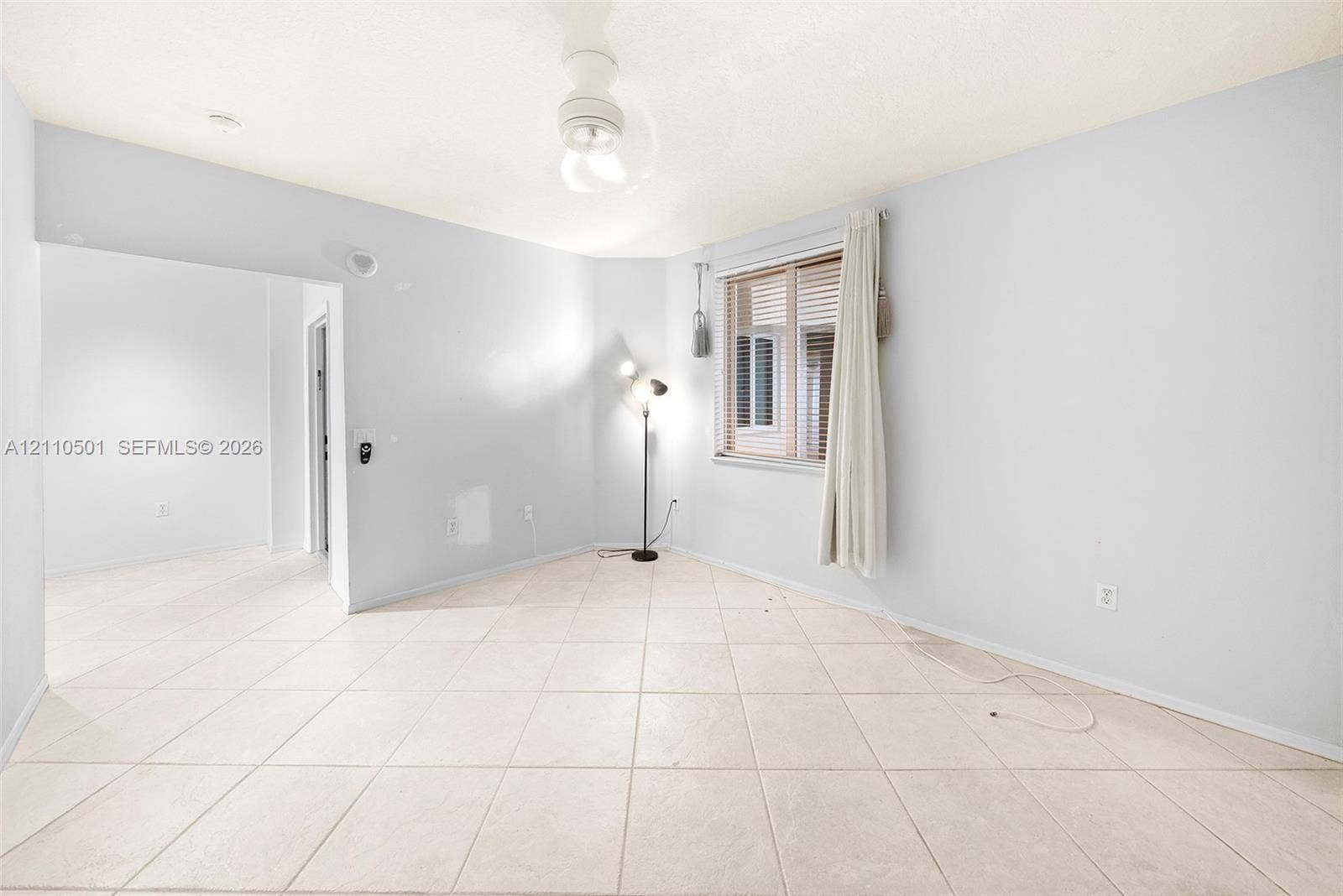 Neutral-toned ceramic tile flooring, ceiling-mounted light fixture, and horizontal blind window covering
