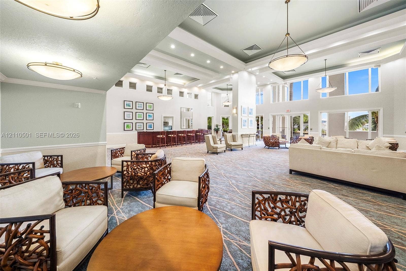 Expansive room featuring recessed lighting, tray ceilings, oversized windows, and a built-in bar area with custom cabinetry
