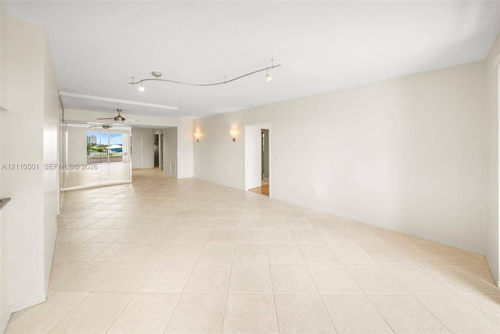 Neutral-toned tile flooring, recessed track lighting, wall-mounted sconces, and full-length mirrored paneling