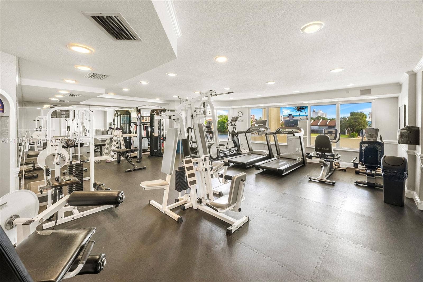 Fitness room featuring a mirrored wall, recessed lighting, rubberized flooring, and large windows