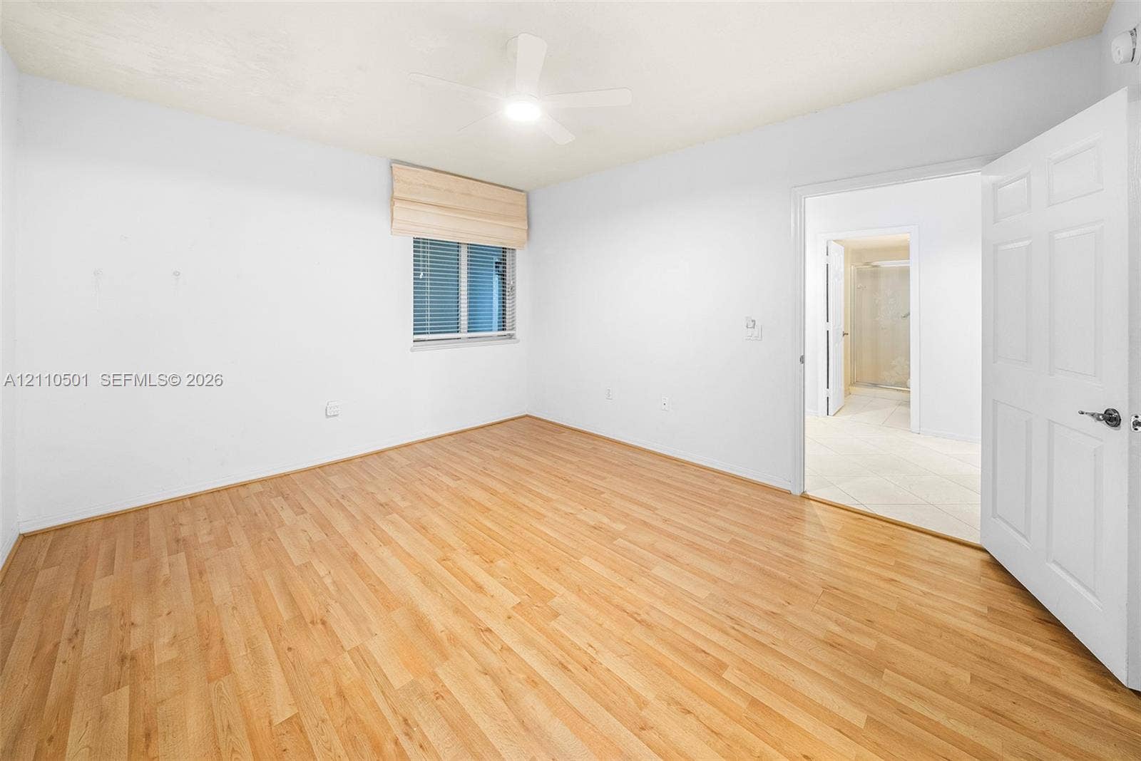 Wood-finish flooring, central ceiling fan with integrated lighting, and a neutral color palette