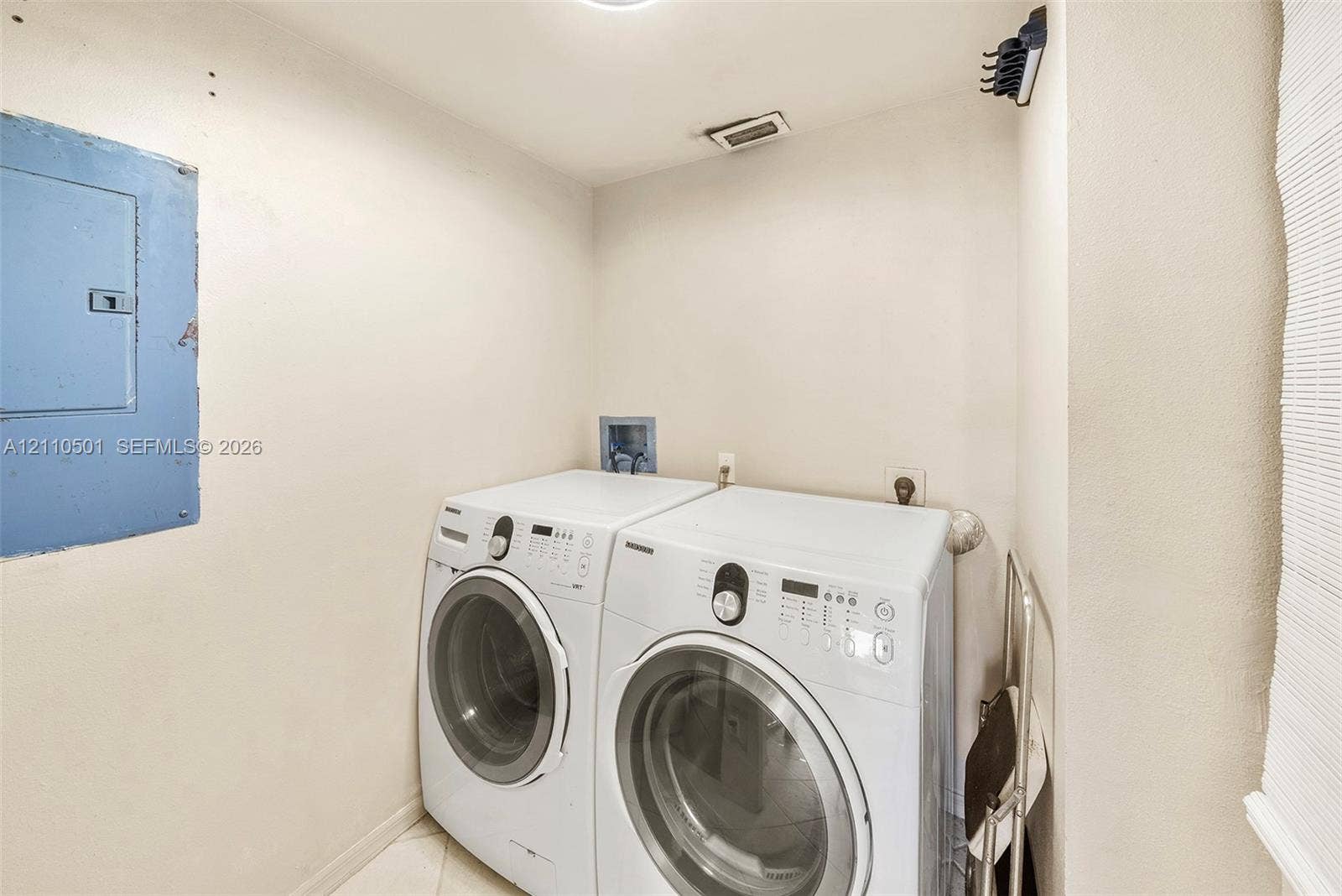 Dedicated utility area featuring white washer and dryer, tiled flooring, and an integrated electrical panel