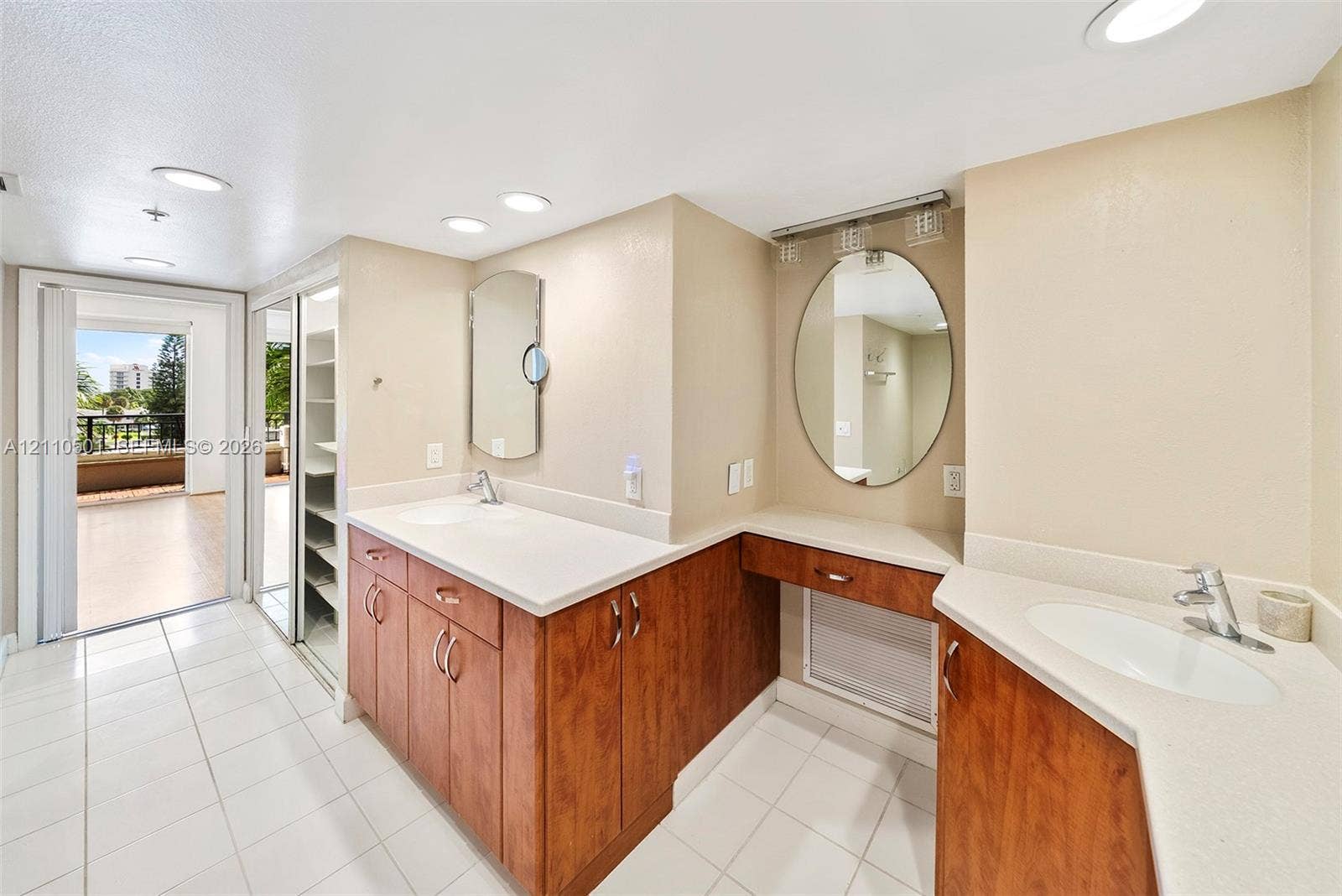Dual-sink vanity with wood-finish cabinetry, solid surface countertops, recessed lighting, and tile flooring