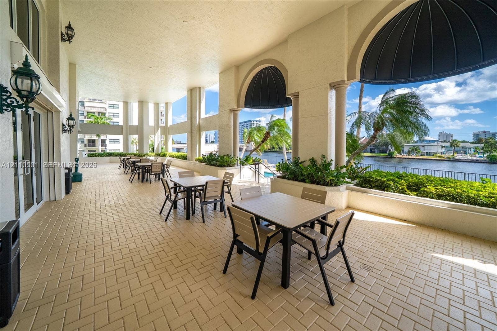 Covered outdoor terrace featuring arched architectural detailing, built-in masonry planters, decorative dome awnings, and tiled flooring