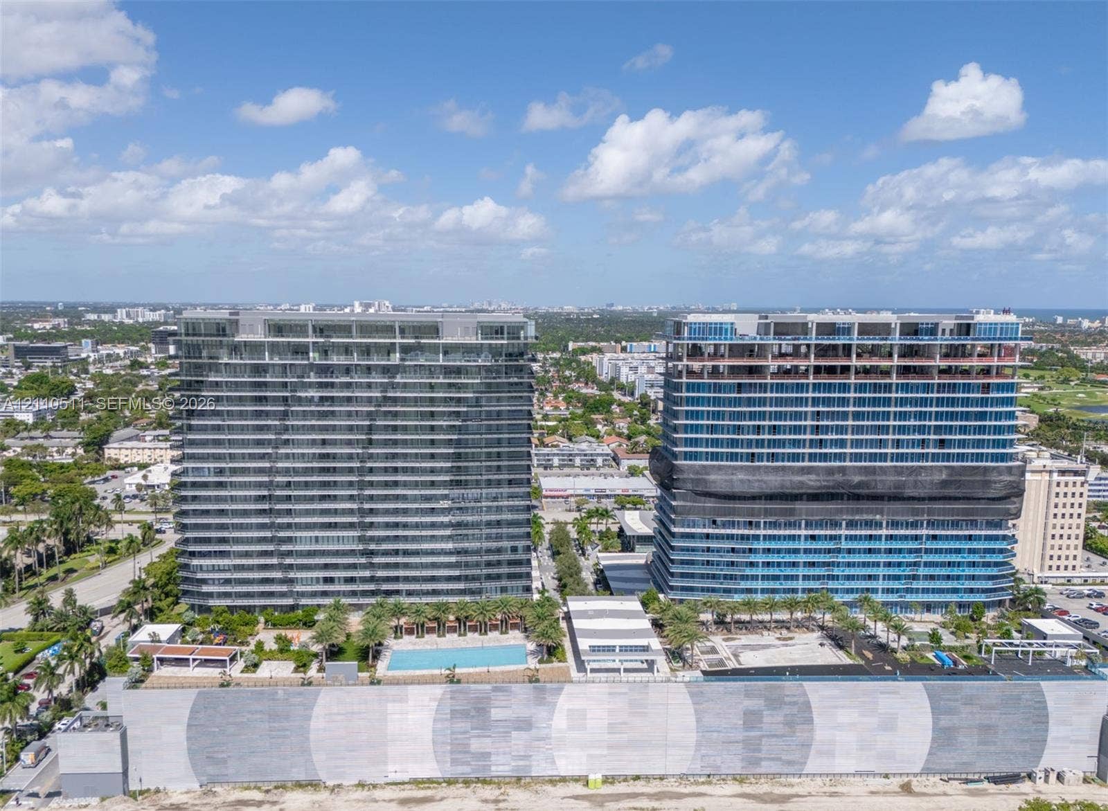 1170 E Hallandale Beach Boulevard, #1208, Hallandale Beach, FL 33009 High-rise residential towers featuring expansive glass curtain wall facades, integrated swimming pool, landscaped outdoor ground-level area, and concrete perimeter retaining walls