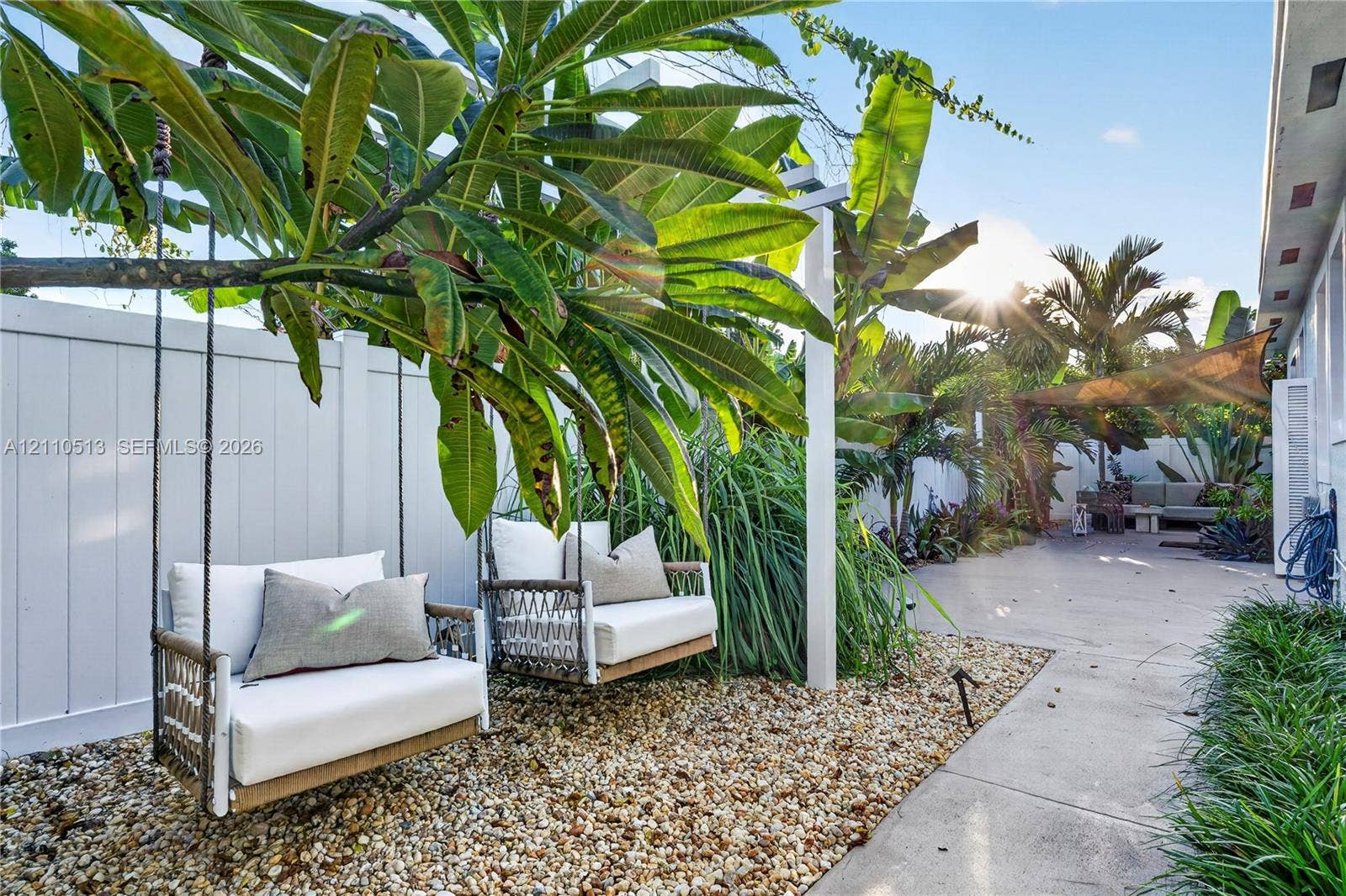 6520 SW 16th Terrace, West Miami, FL 33155 Private rear outdoor space featuring a paved patio, decorative gravel ground cover, a perimeter privacy fence, and mature tropical landscaping