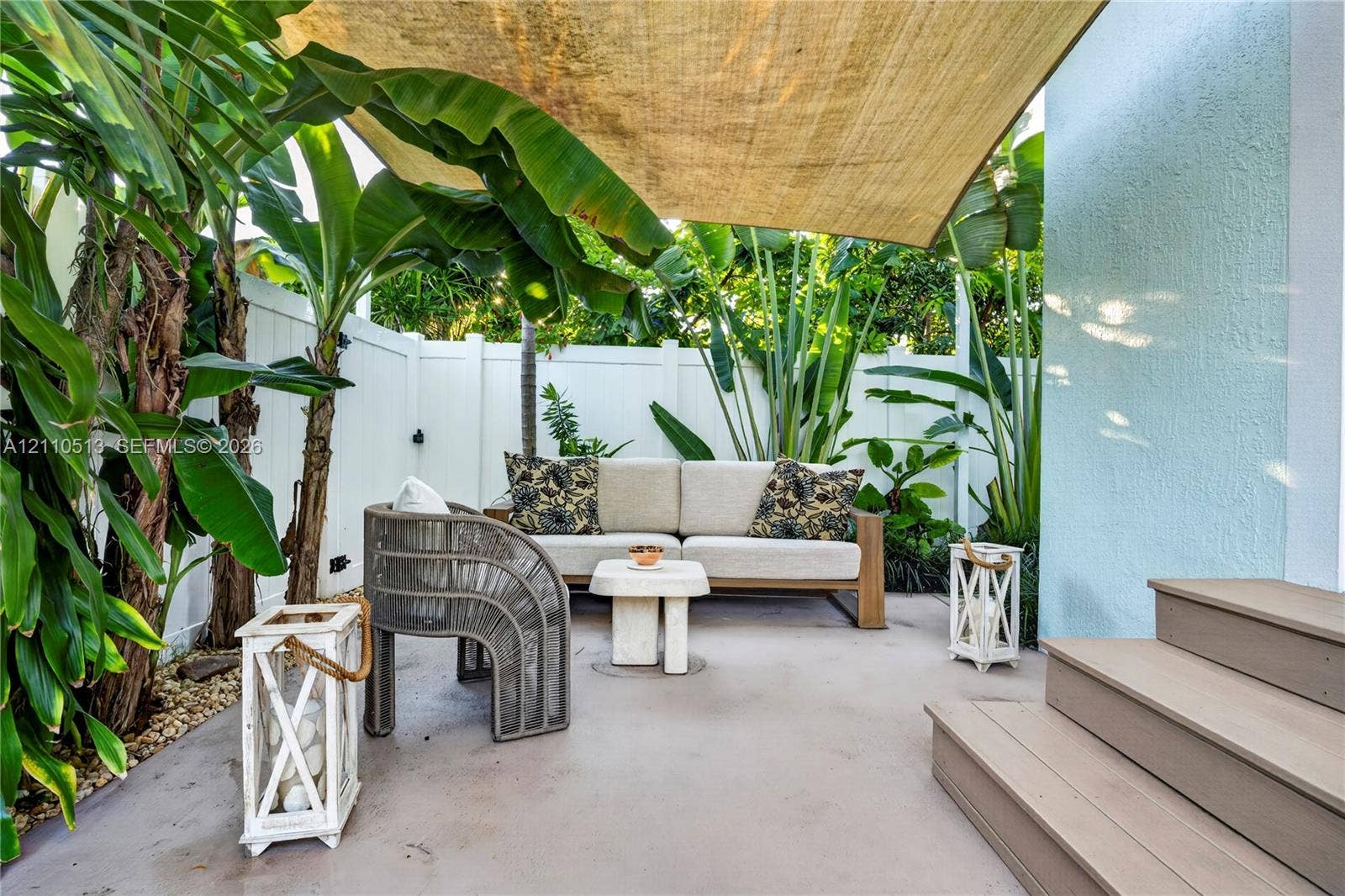 6520 SW 16th Terrace, West Miami, FL 33155 Private outdoor patio featuring a concrete surface, overhead shade sail, white vinyl privacy fencing, and exterior composite steps