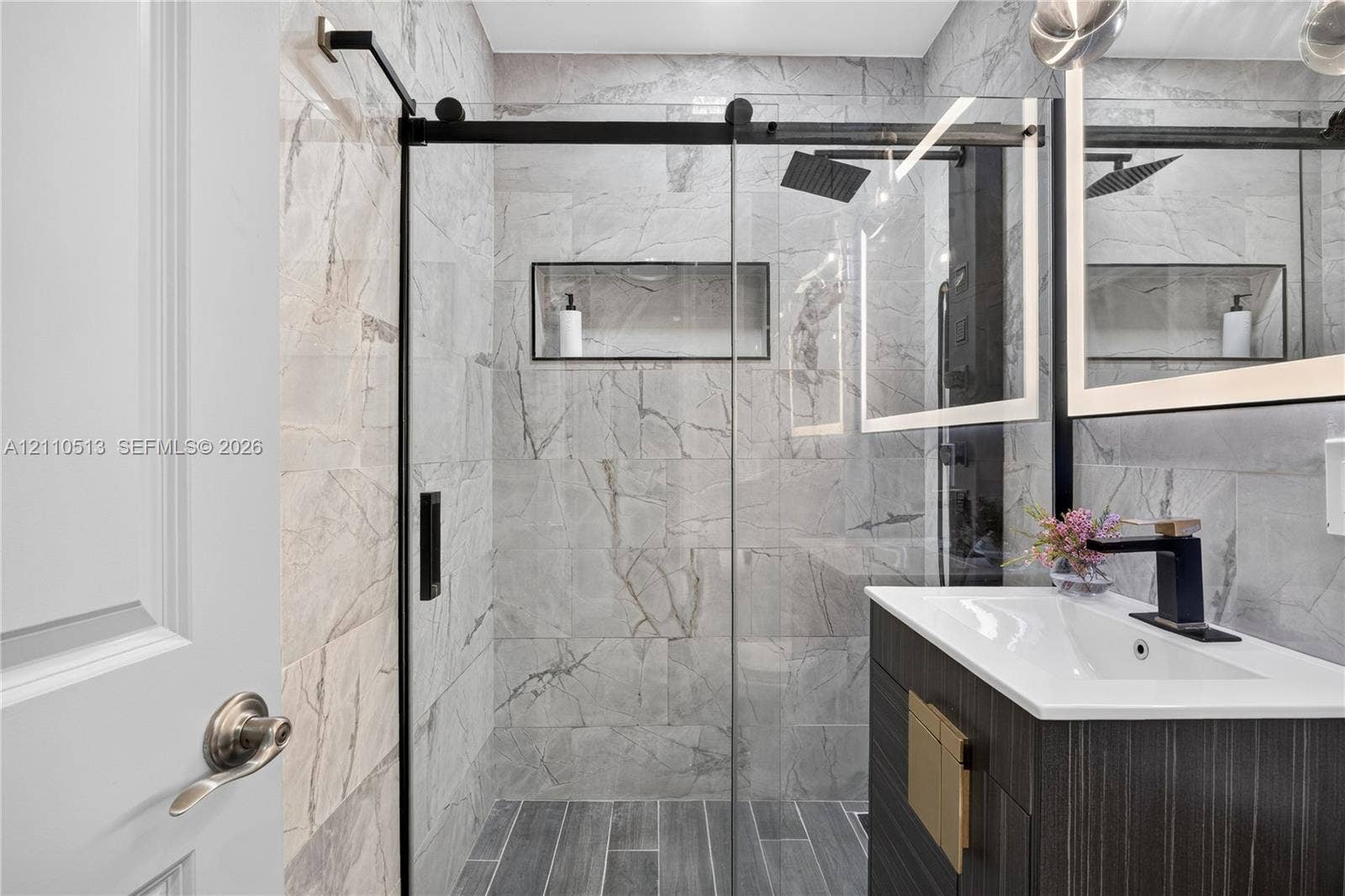 6520 SW 16th Terrace, West Miami, FL 33155 Walk-in shower with floor-to-ceiling large-format tile, glass sliding door, and recessed wall niche