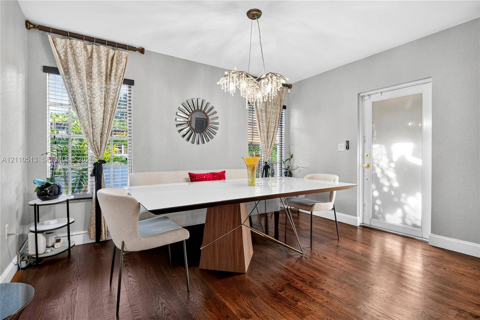 6520 SW 16th Terrace, West Miami, FL 33155 Dining area featuring wood-finish flooring, multi-pane windows with horizontal blinds, a decorative multi-light chandelier, and a glass-paneled exterior door