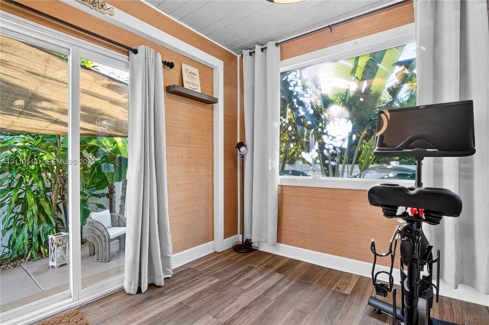 6520 SW 16th Terrace, West Miami, FL 33155 Interior space featuring horizontal wood-finish wall paneling, plank-style wood-finish flooring, a white tongue-and-groove ceiling, sliding glass doors, and a large picture window