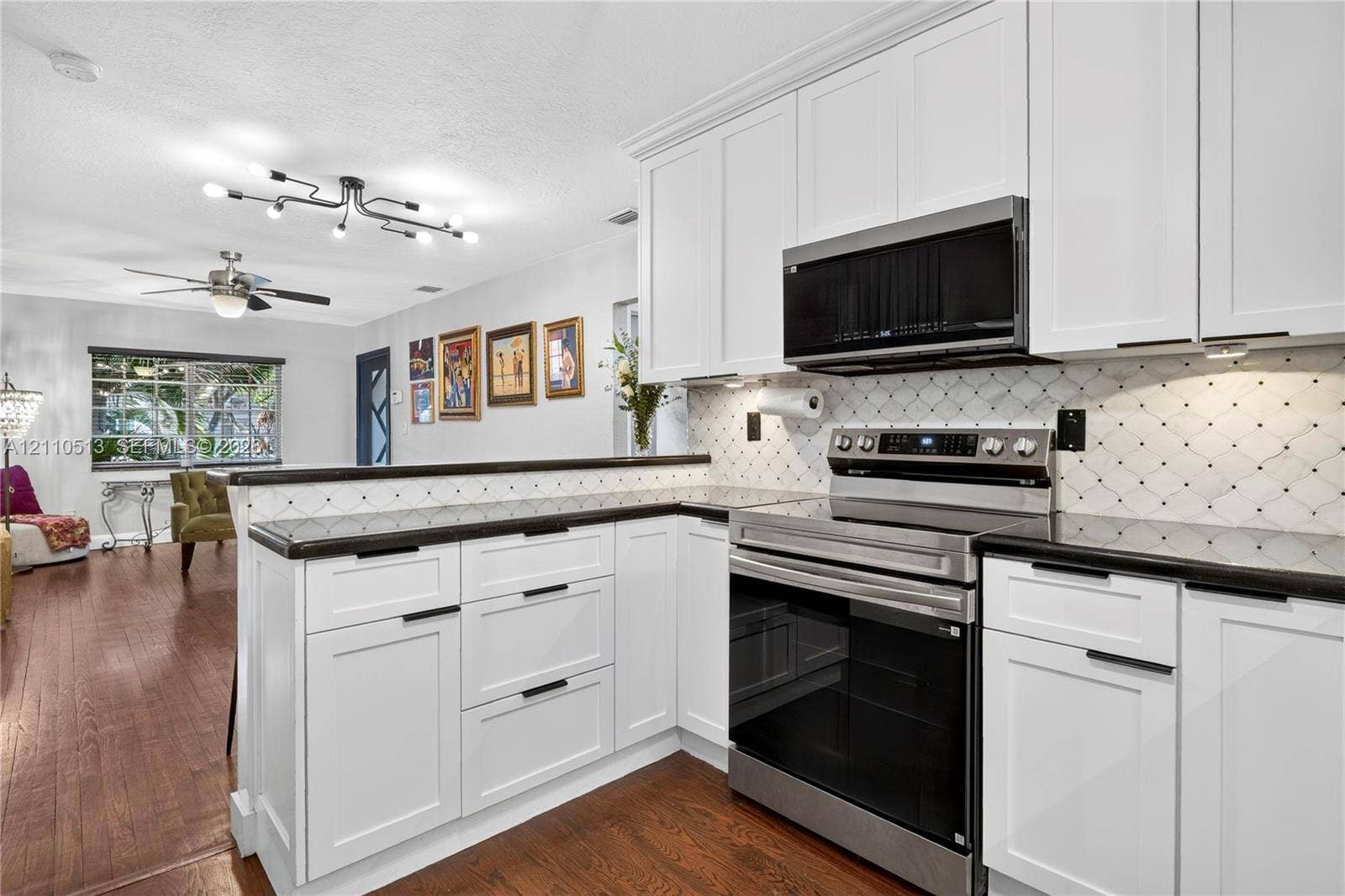 6520 SW 16th Terrace, West Miami, FL 33155 White shaker-style cabinetry, dark stone countertops, patterned tile backsplash, stainless steel appliances, and wood-finish flooring