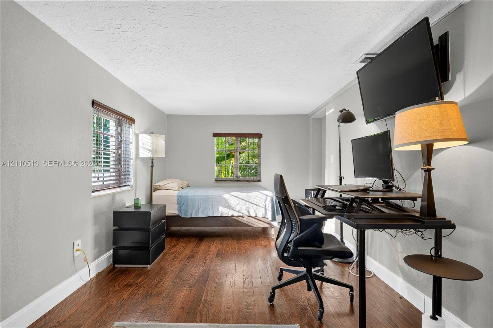 6520 SW 16th Terrace, West Miami, FL 33155 Interior room featuring wood-finish flooring, neutral walls, and two windows with horizontal blinds