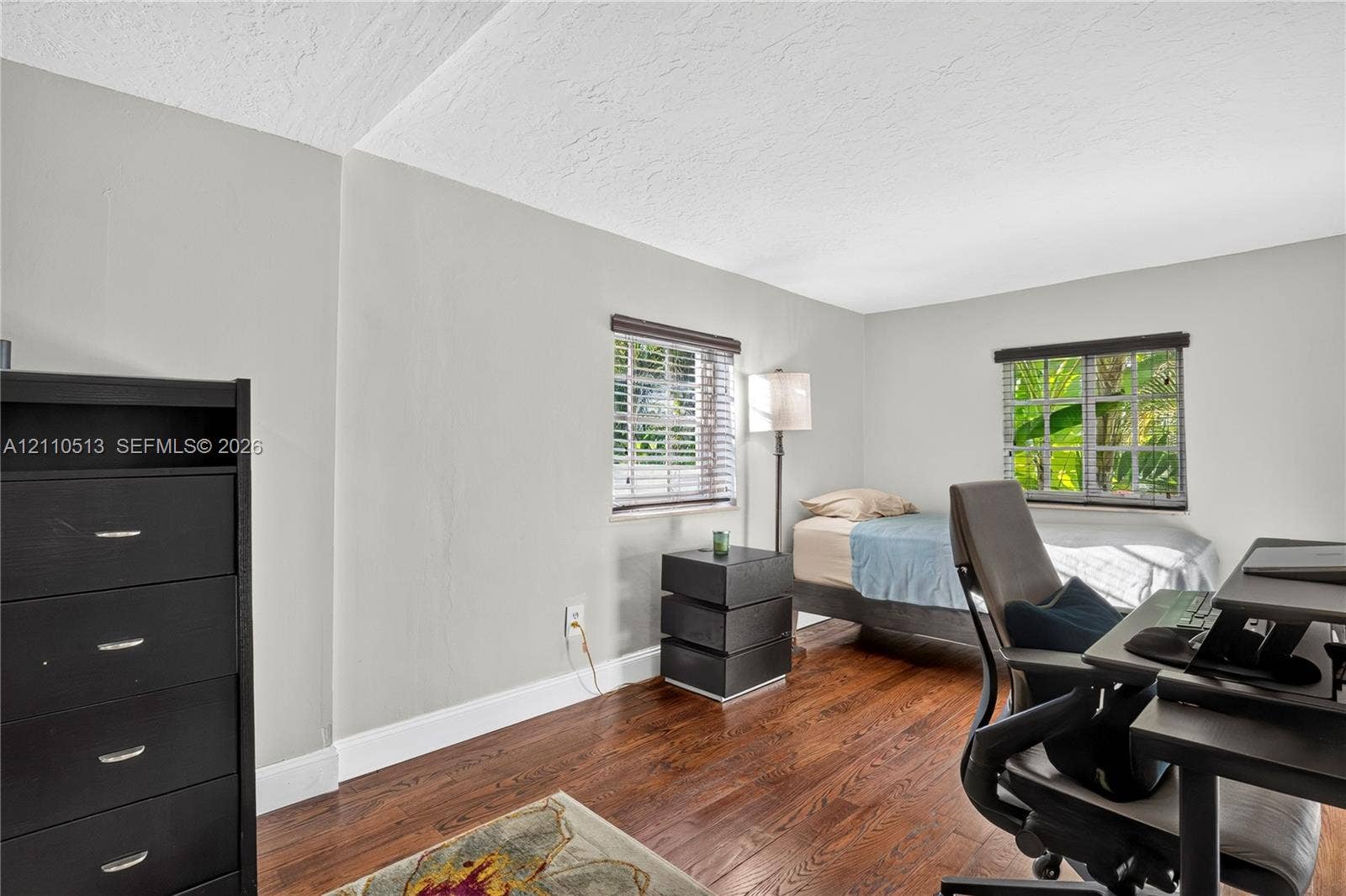 6520 SW 16th Terrace, West Miami, FL 33155 Room interior featuring wood-finish flooring, two windows with horizontal blinds, and neutral wall tones