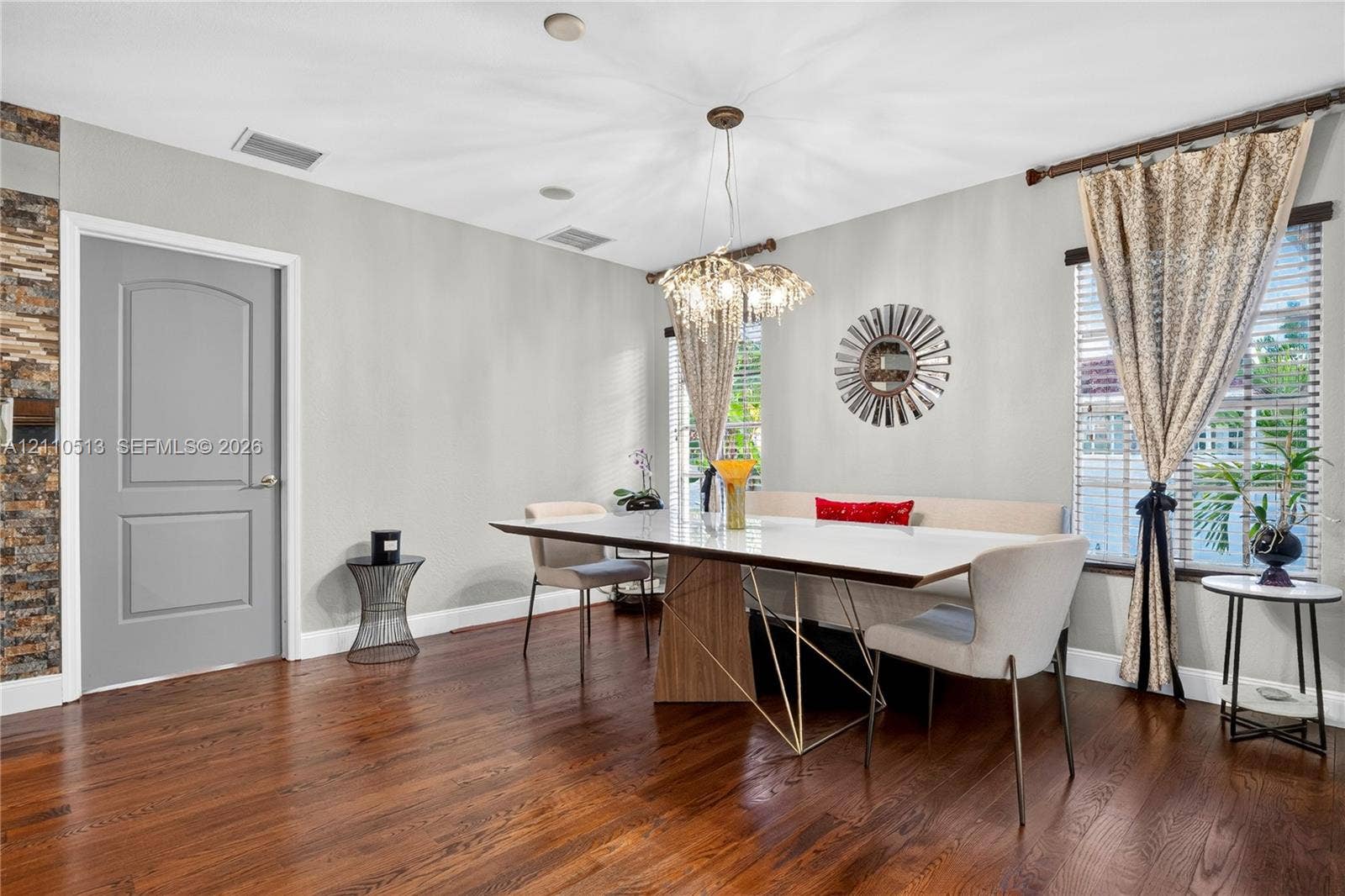6520 SW 16th Terrace, West Miami, FL 33155 Wood-finish flooring, multi-faceted crystal pendant lighting, stacked-stone accent wall, and arch-top door