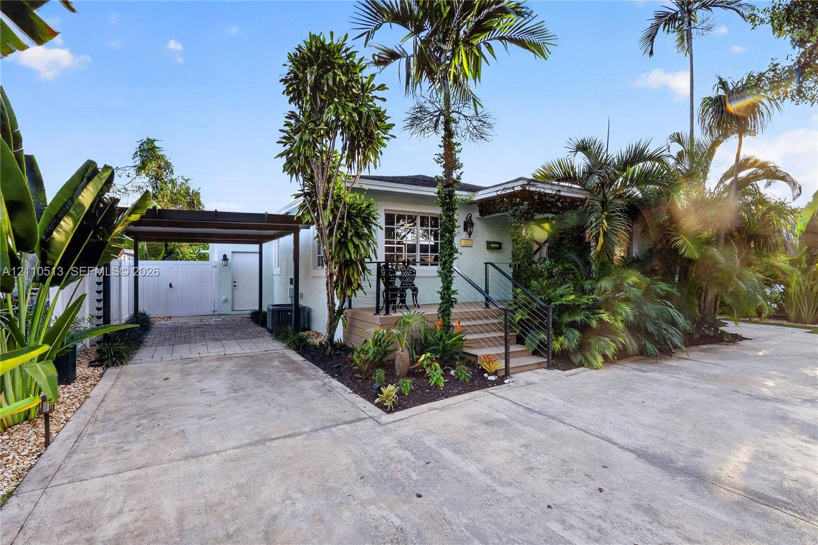 6520 SW 16th Terrace, West Miami, FL 33155 Exterior featuring a covered carport, raised wooden entryway deck, metal cable railing, and tropical landscaping