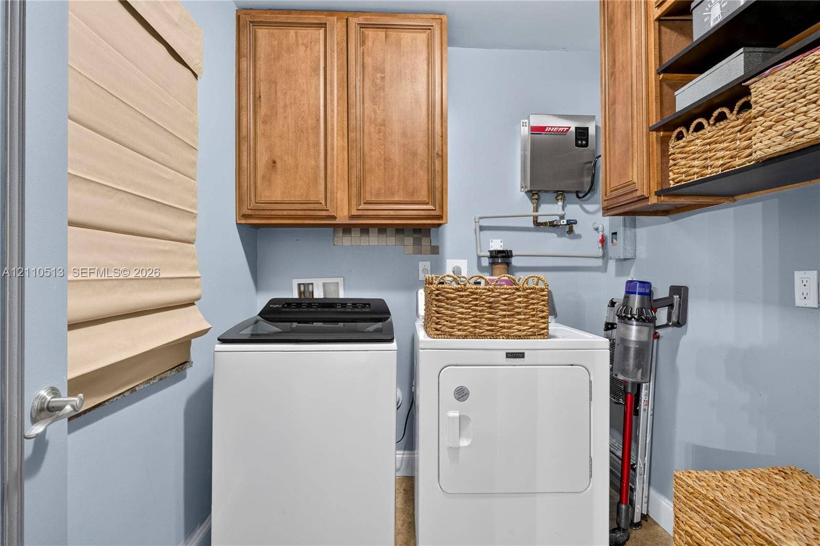 6520 SW 16th Terrace, West Miami, FL 33155 Laundry room featuring wood-finish wall-mounted cabinetry, integrated open shelving, and a tankless water heater