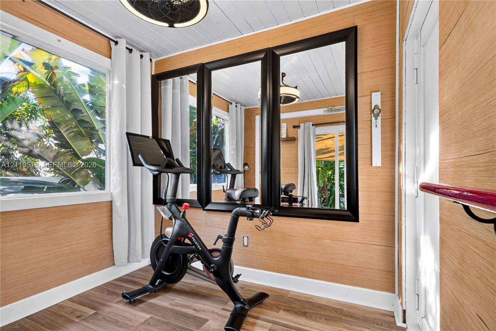 6520 SW 16th Terrace, West Miami, FL 33155 Horizontal wood-plank wall paneling, wood-finish flooring, white beadboard ceiling, and large, black-framed wall mirrors