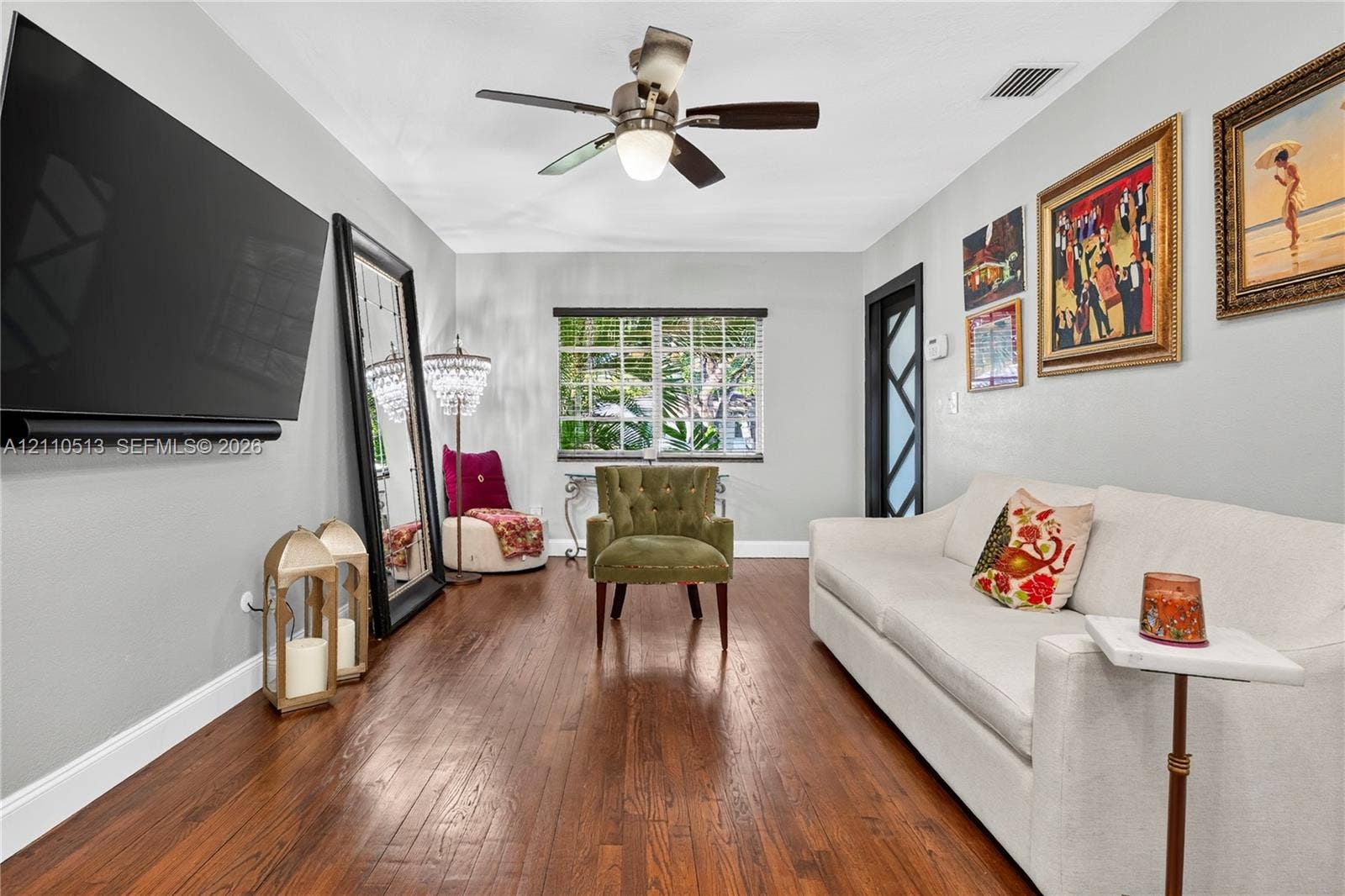 6520 SW 16th Terrace, West Miami, FL 33155 Room featuring wood-finish flooring, a multi-pane window with exterior greenery, and a ceiling-mounted light fixture with a central fan