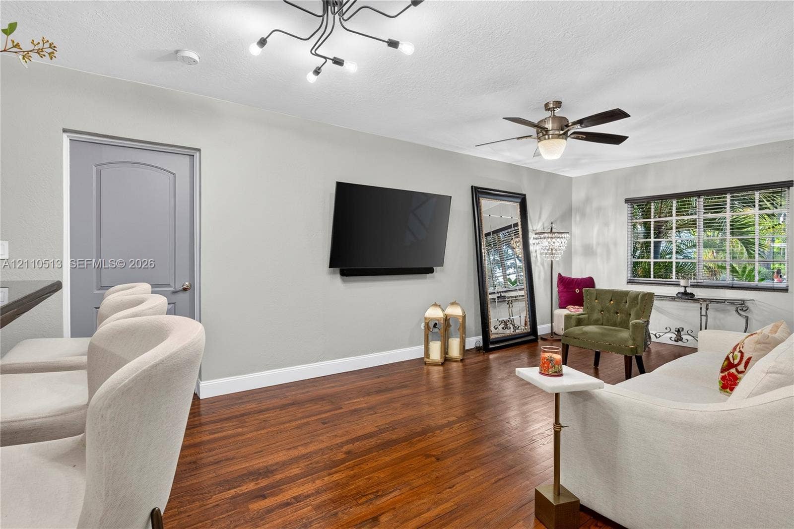 6520 SW 16th Terrace, West Miami, FL 33155 Living area featuring wood-finish flooring, a multi-arm modern light fixture, a ceiling fan, and a grid-pane window
