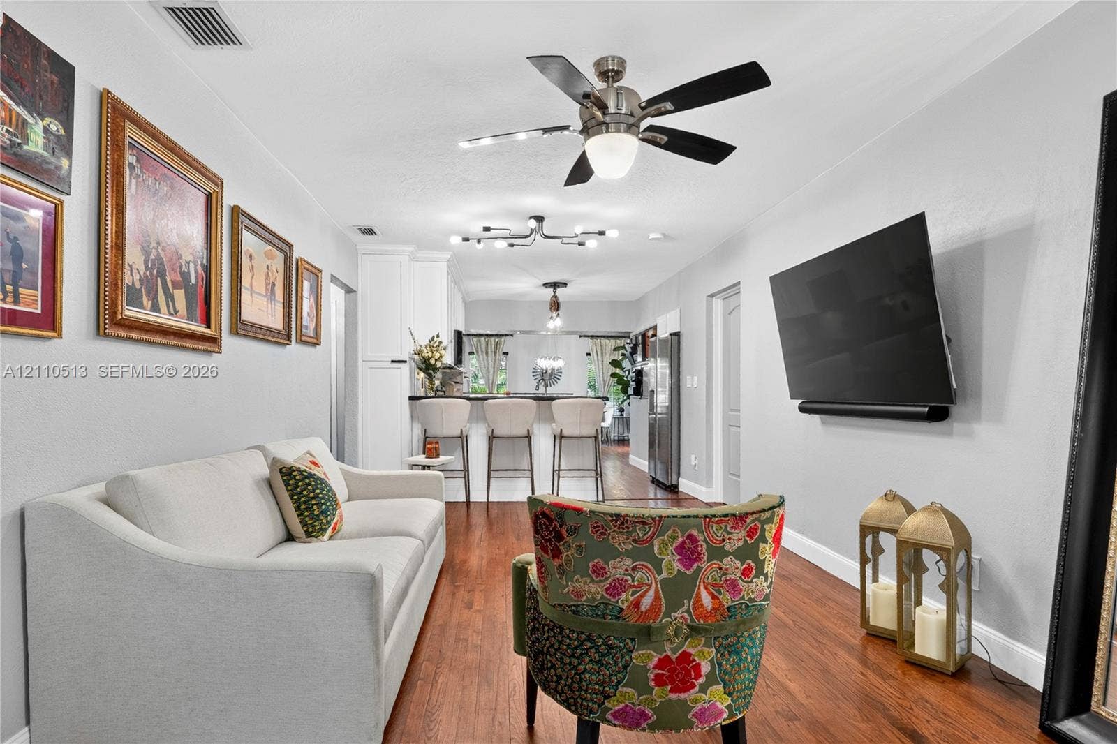 6520 SW 16th Terrace, West Miami, FL 33155 Wood-finish flooring, brushed nickel ceiling fan, multi-bulb modern chandelier, and kitchen breakfast bar with built-in cabinetry