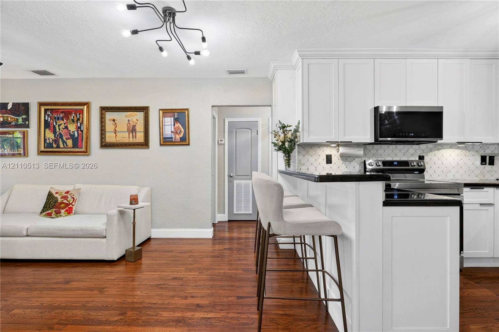 6520 SW 16th Terrace, West Miami, FL 33155 Kitchen featuring white shaker-style cabinetry, dark stone countertops, a geometric-pattern tile backsplash, stainless steel appliances, and wood-finish flooring