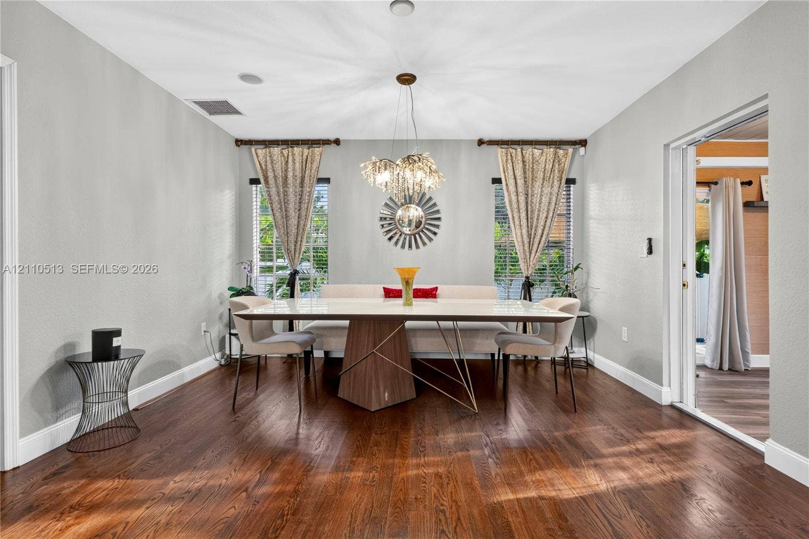 6520 SW 16th Terrace, West Miami, FL 33155 Dining space featuring wood-finish flooring, dual windows with decorative rods, and a suspended multi-light fixture