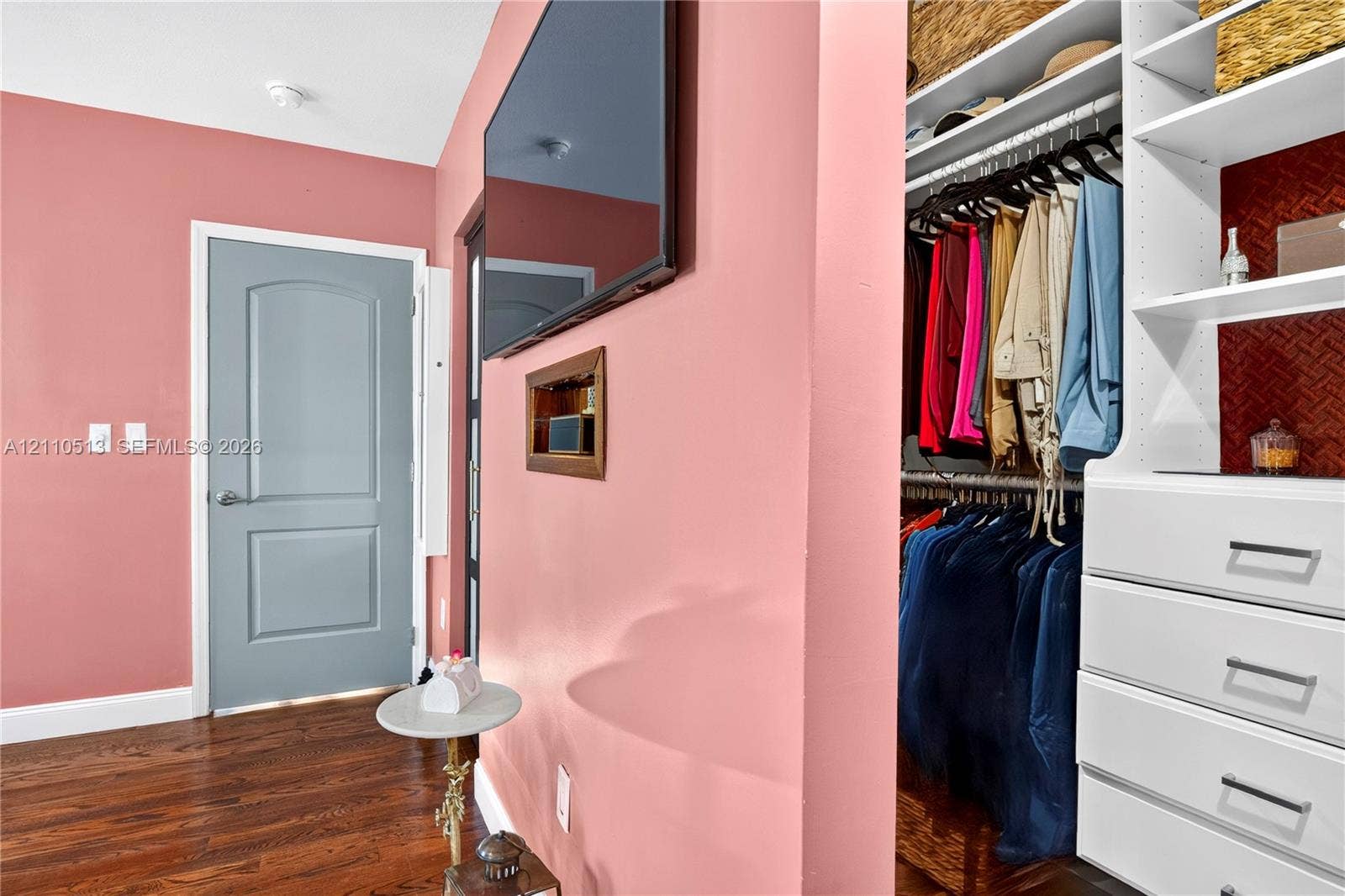 6520 SW 16th Terrace, West Miami, FL 33155 Custom built-in closet featuring white cabinetry, multiple shelving tiers, and integrated drawers with metal pulls, finished with wood-finish flooring and a paneled interior door