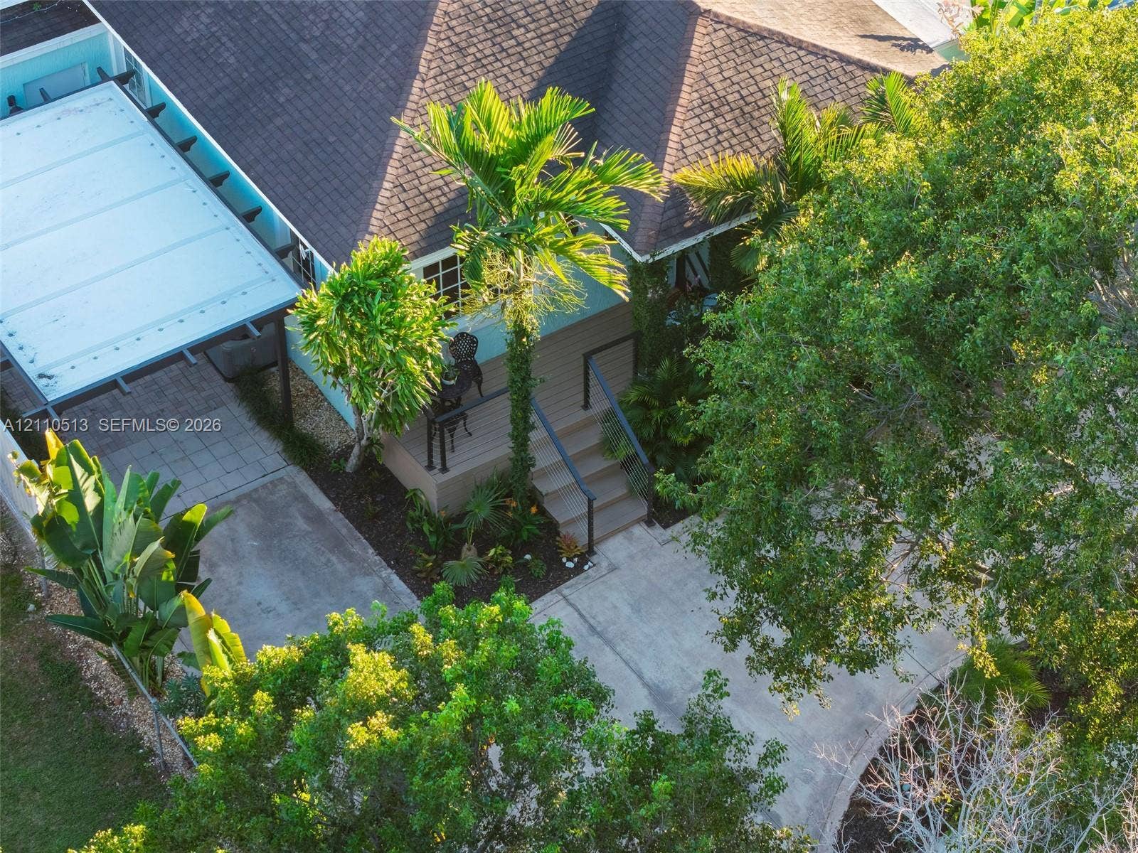 6520 SW 16th Terrace, West Miami, FL 33155 Exterior features include a concrete driveway, a covered parking structure, a wooden front deck with stairs, and mature landscaping
