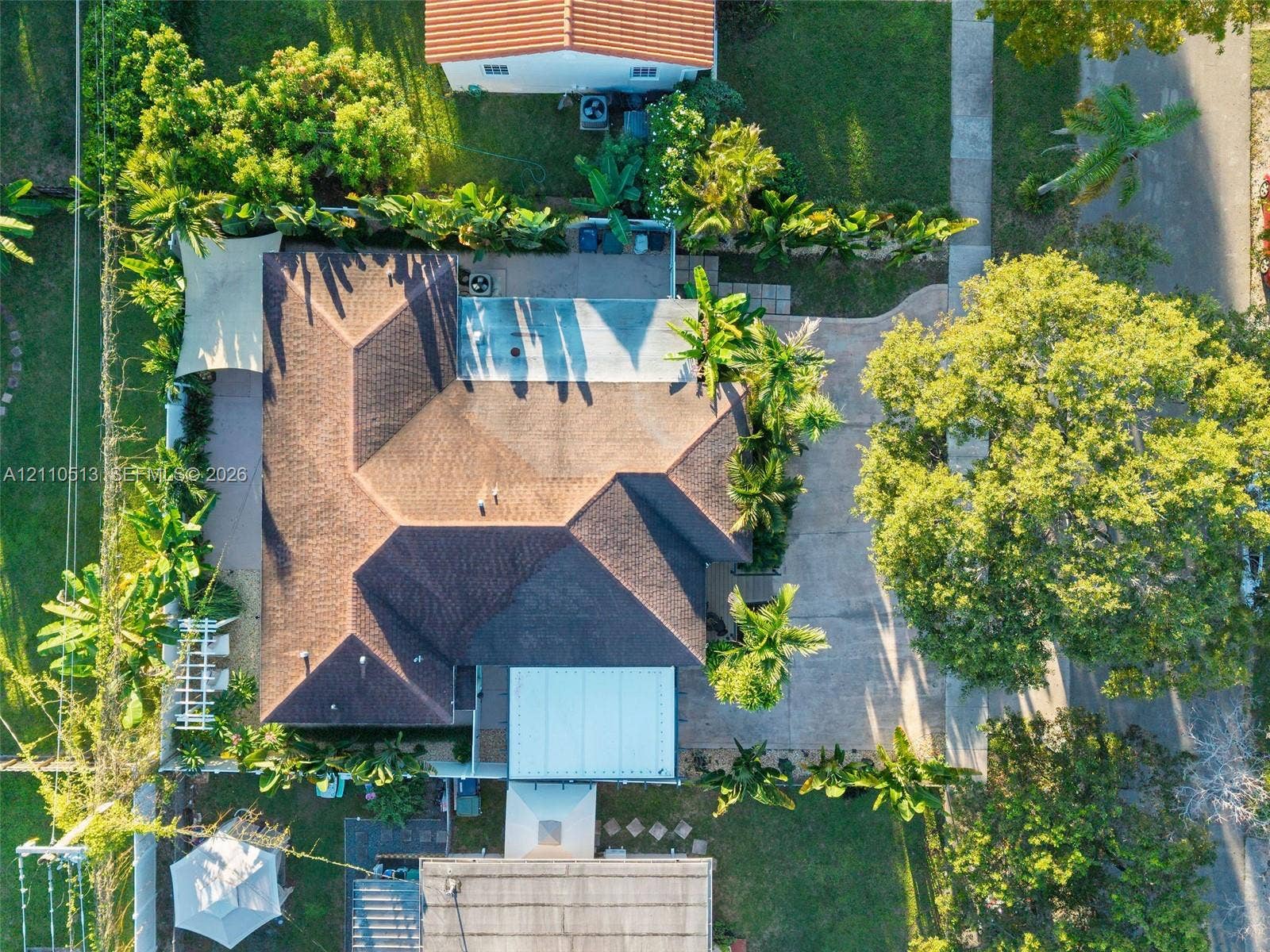 6520 SW 16th Terrace, West Miami, FL 33155 Aerial perspective featuring a multi-faceted shingle roof, concrete driveway, paved exterior patio, and mature landscaping