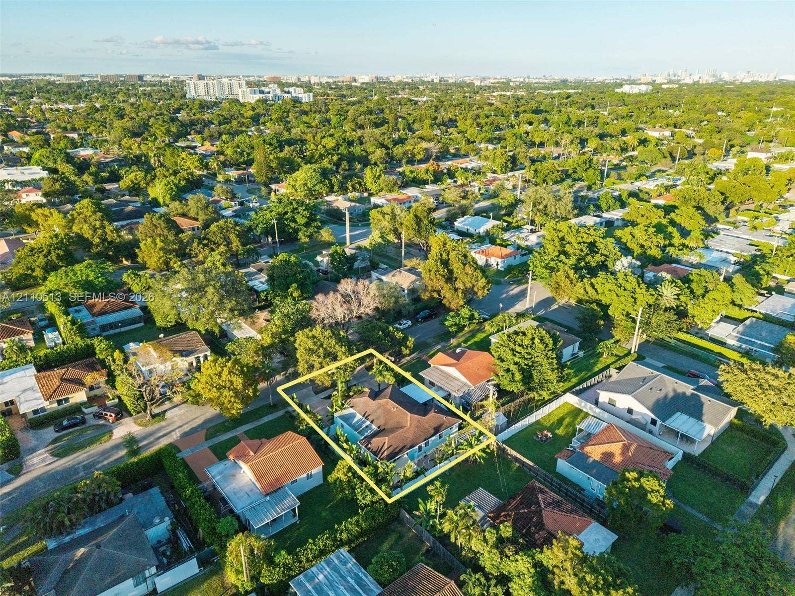 6520 SW 16th Terrace, West Miami, FL 33155 Aerial perspective of a residential property featuring a pitched roofline, paved driveway, enclosed backyard, and mature landscaping