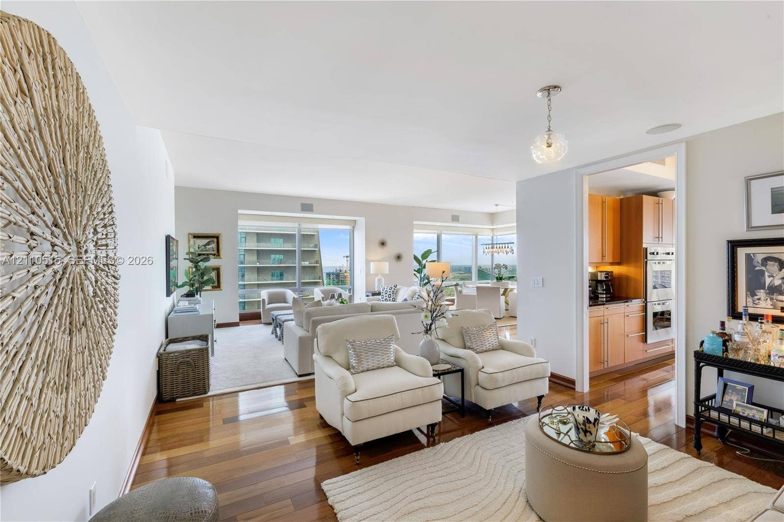 Polished wood-finish flooring, floor-to-ceiling windows, and natural light exposure, with built-in cabinetry and stainless steel wall-mounted oven in the kitchen