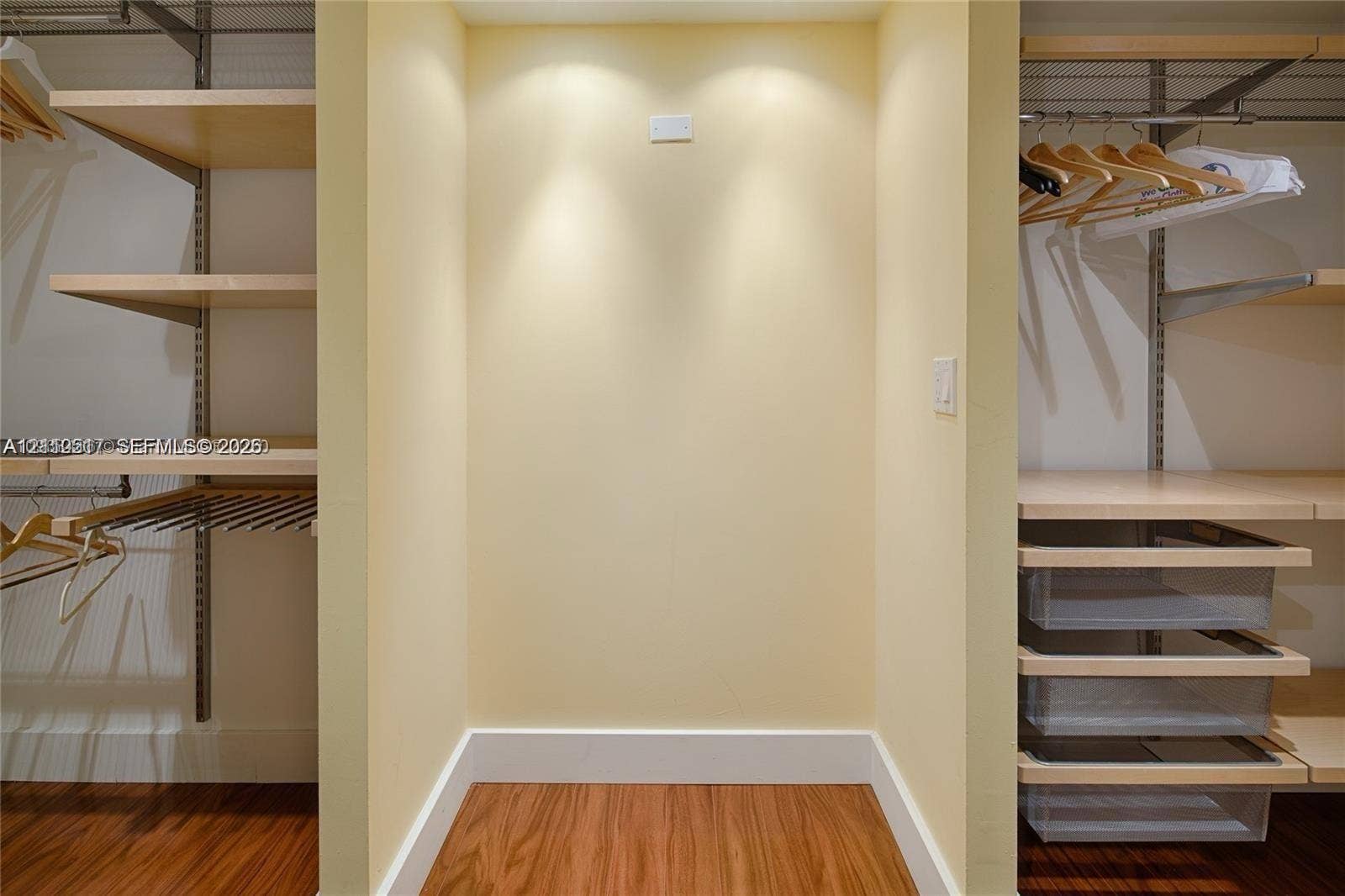 Walk-in closet featuring adjustable light wood-finish shelving, integrated hanging rods, and built-in translucent sliding storage drawers with wood-finish flooring
