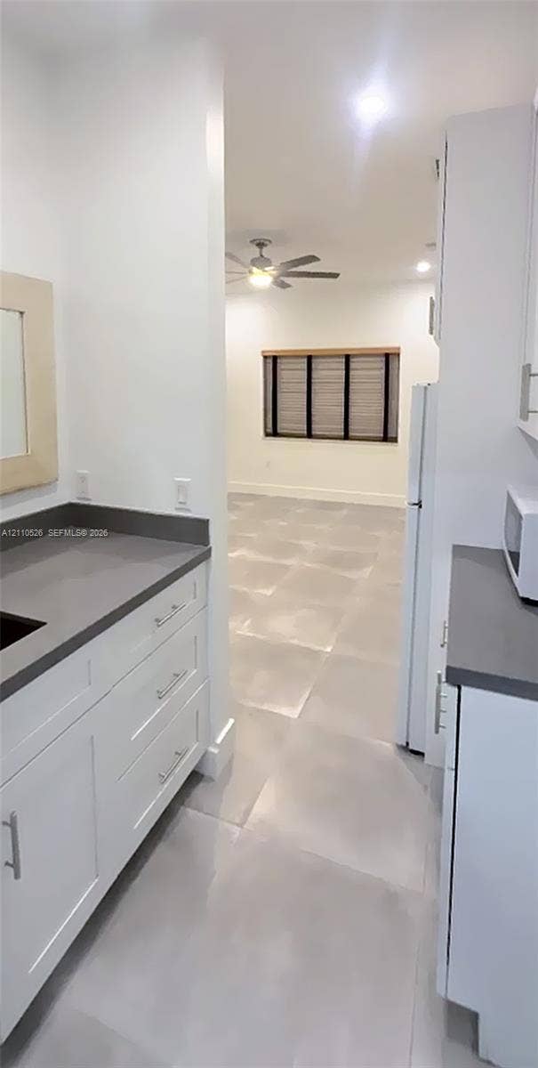 15677 SW 20 Street, #B, Miami, Miami, FL 33185 Kitchen featuring white shaker-style cabinetry, solid-surface countertops, large-format tile flooring, and integrated ceiling lighting