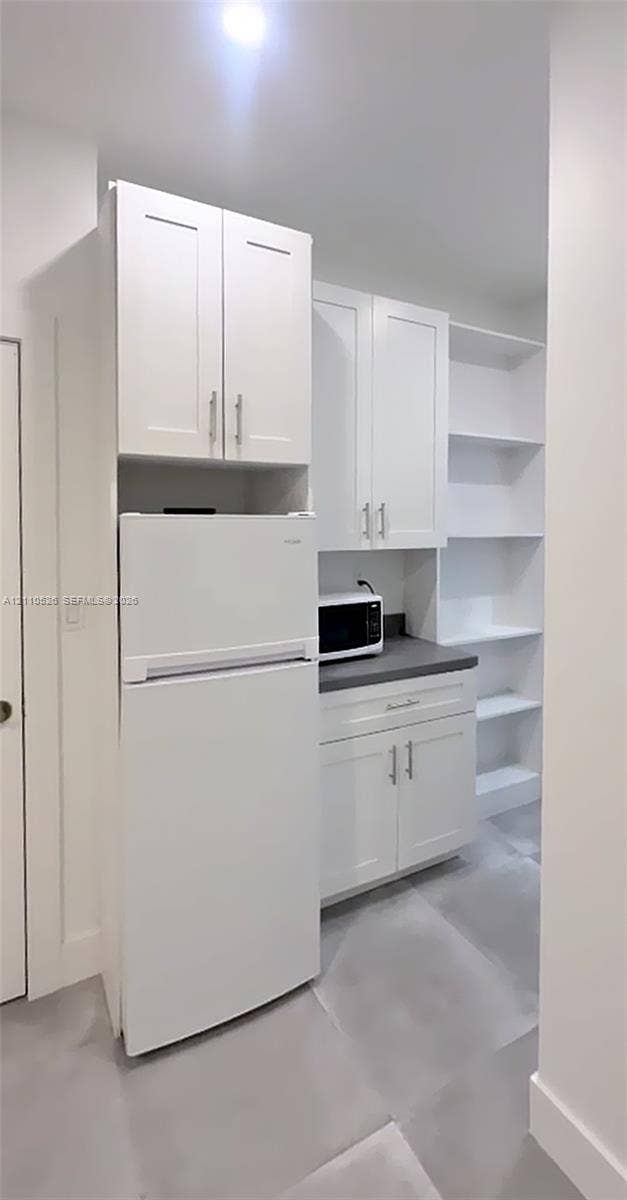 15677 SW 20 Street, #B, Miami, Miami, FL 33185 White cabinetry with brushed metal hardware, dark solid-surface countertop, and built-in open shelving