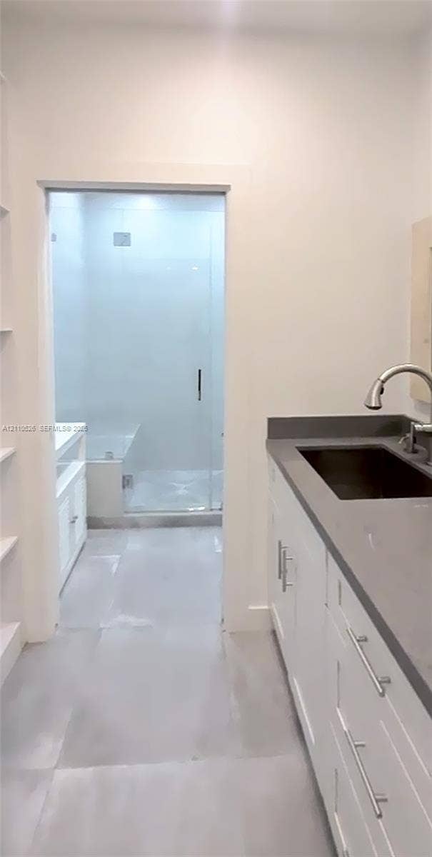 15677 SW 20 Street, #B, Miami, Miami, FL 33185 Bathroom vanity featuring white shaker-style cabinetry, a solid surface countertop, an undermount sink with a gooseneck faucet, and a glass-enclosed shower with tiled walls